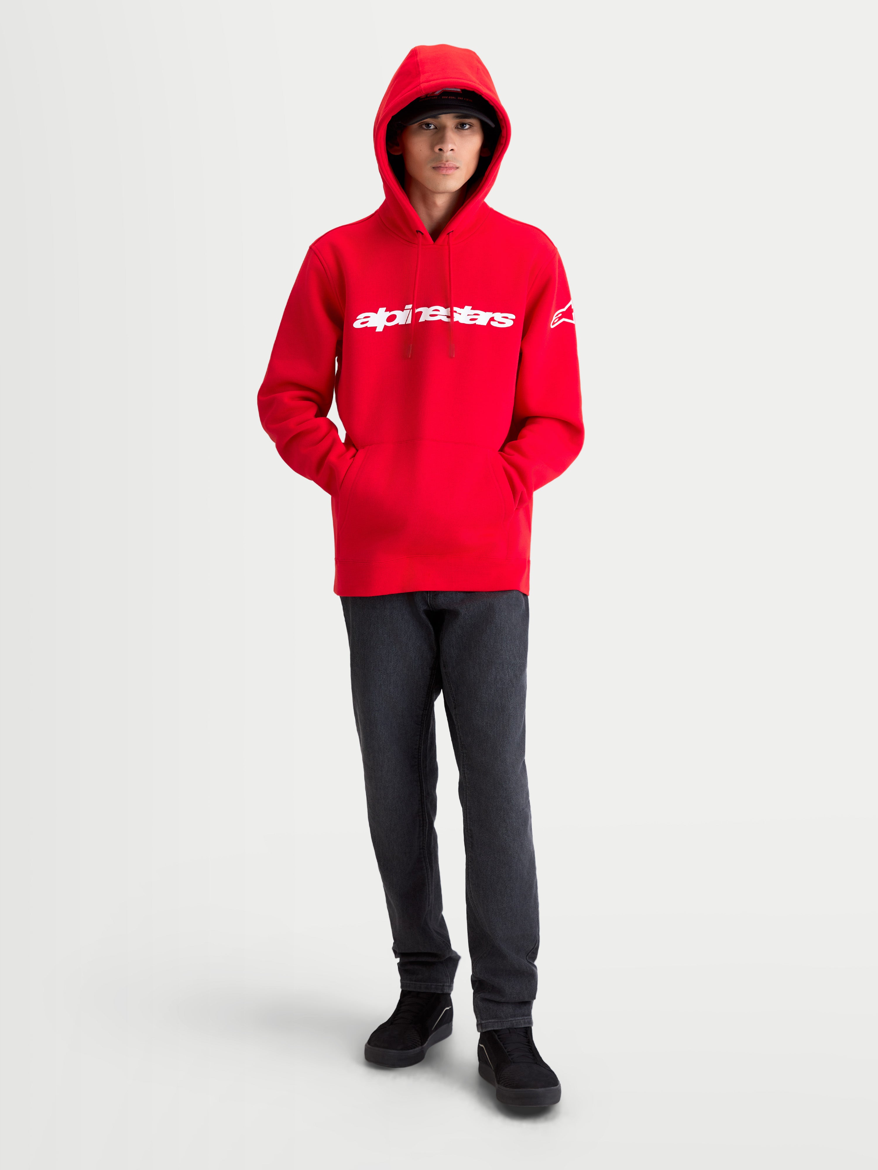 Alpinestars Race Wordmark Hættetrøje, herre-sportstøj i fleece, rød og hvid, motorsportsinspireret fritidstøj. Modellen bærer en rød hættetrøje med hvidt Alpinestars wordmark på brystet, Ageless logo på ærmet og hætte med snoretræk.