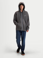 Alpinestars Entity Oversized Hoodie, Premium Motorsport Zip Fleece Sportswear, Charcoal Gray, featuring a Vislon front zipper, self-lined hood with flat drawcords, and kangaroo pocket. On-model view showing the relaxed, oversized silhouette with embroidered Astars logo on the chest and sleeve.