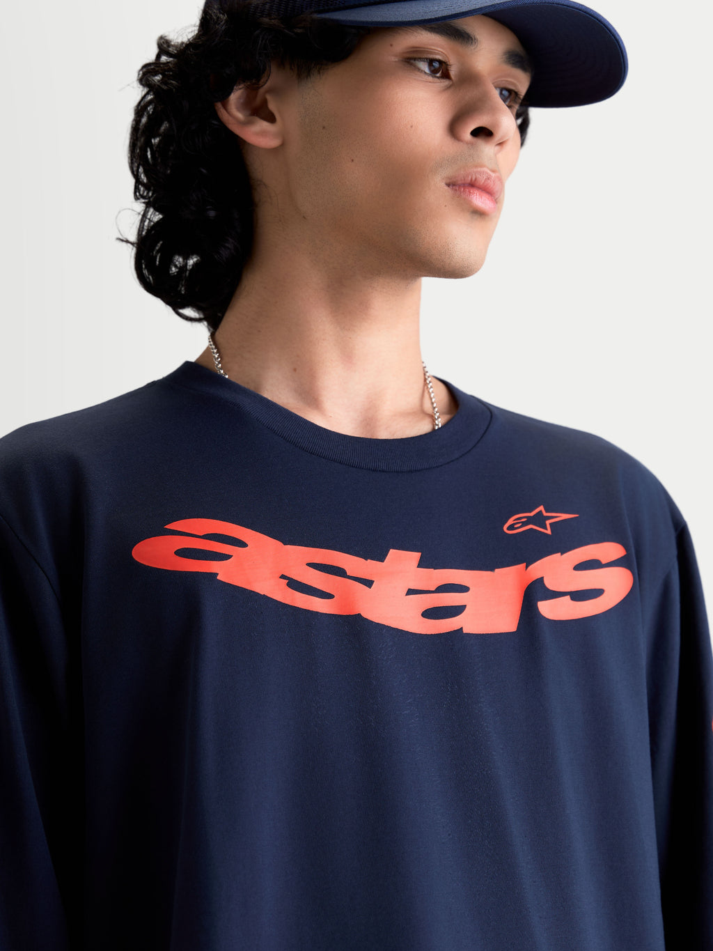 Alpinestars Velocifier CSF langærmet trøje, motorsportsinspireret sportswear på model, marineblå med buet orange Astars-grafik på brystet, blød bomuldsblanding