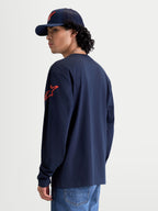 Alpinestars Velocifier CSF T-shirt, langærmet sportswear-t-shirt i marineblå og rød, med rødt Astars-logo på skulderen og ribmanchetter, set bagfra på model, fremstillet af 80 % bomuld og 20 % genanvendt polyester.