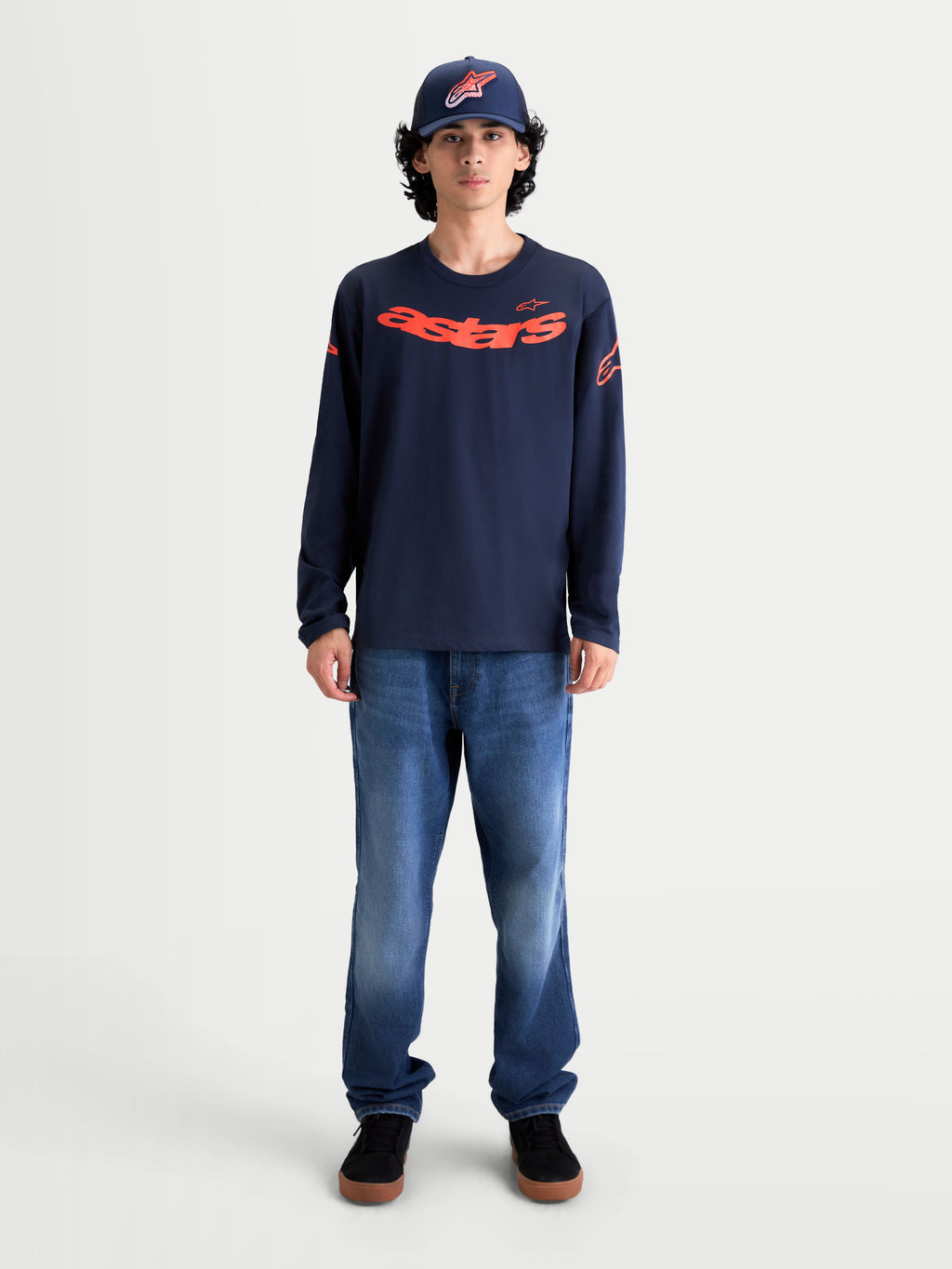 Alpinestars Velocifier CSF langærmet t-shirt, marineblå med rød buet Astars-grafik på brystet og logoer på skuldrene. Herremodel iført sportswear-trøje i blød bomuldsblanding til afslappet hverdagsbrug, motorsport-inspireret design.