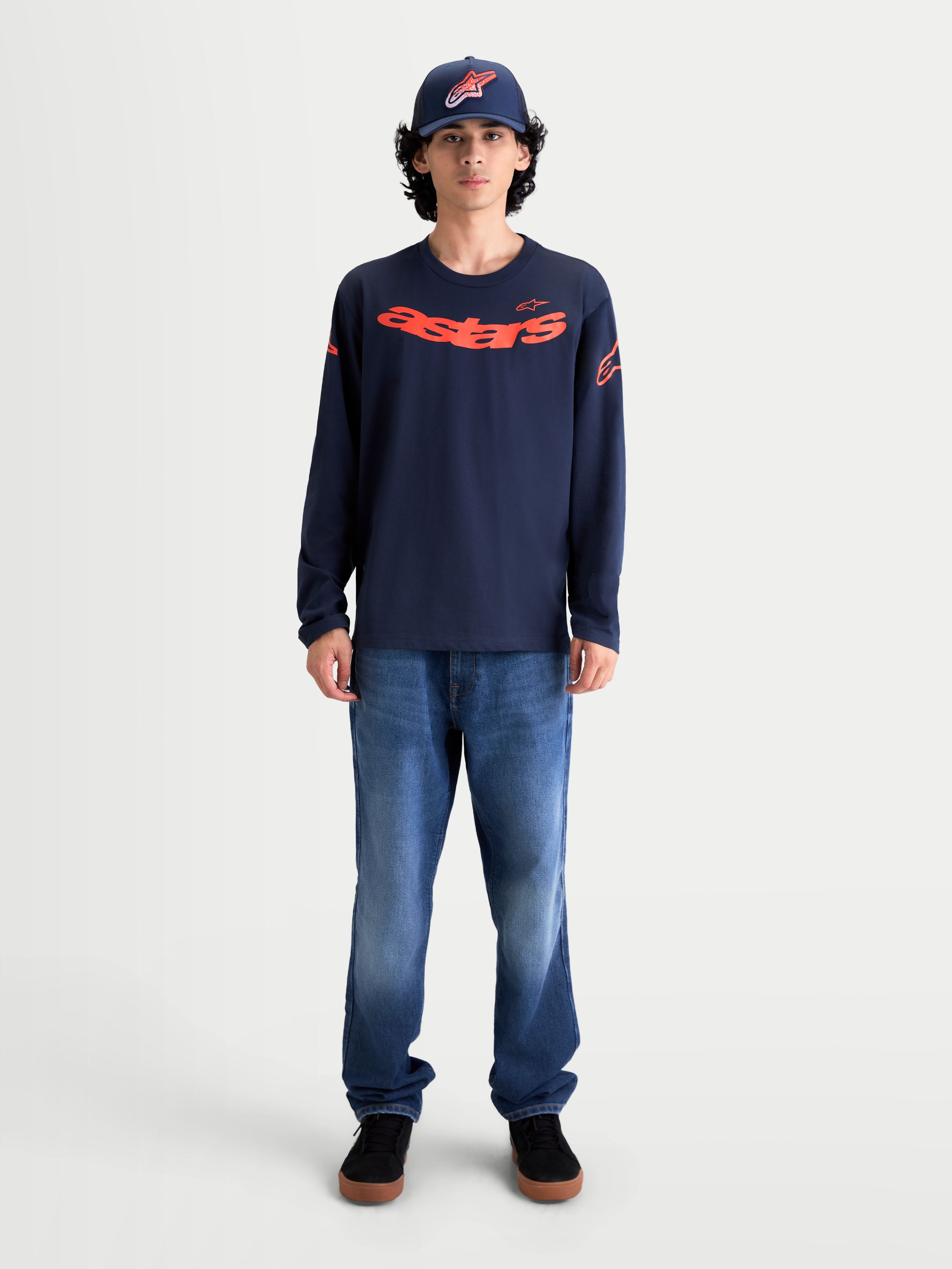 Alpinestars Velocifier CSF langærmet t-shirt, marineblå med rød buet Astars-grafik på brystet og logoer på skuldrene. Herremodel iført sportswear-trøje i blød bomuldsblanding til afslappet hverdagsbrug, motorsport-inspireret design.