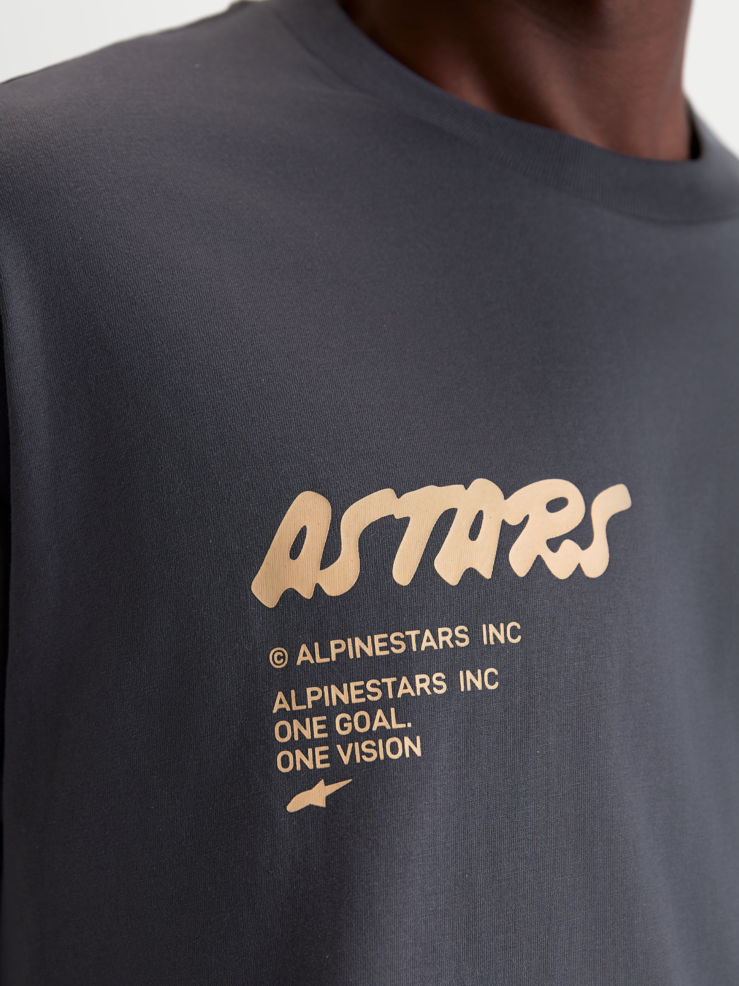 Alpinestars Chalk Oversized CSF T-shirt, kortærmet livsstils-T-shirt, mørkegrå og tan, nærbillede af Astars-logo og One Goal One Vision branding på brystet, oversized fit motorsport-inspireret sportswear.