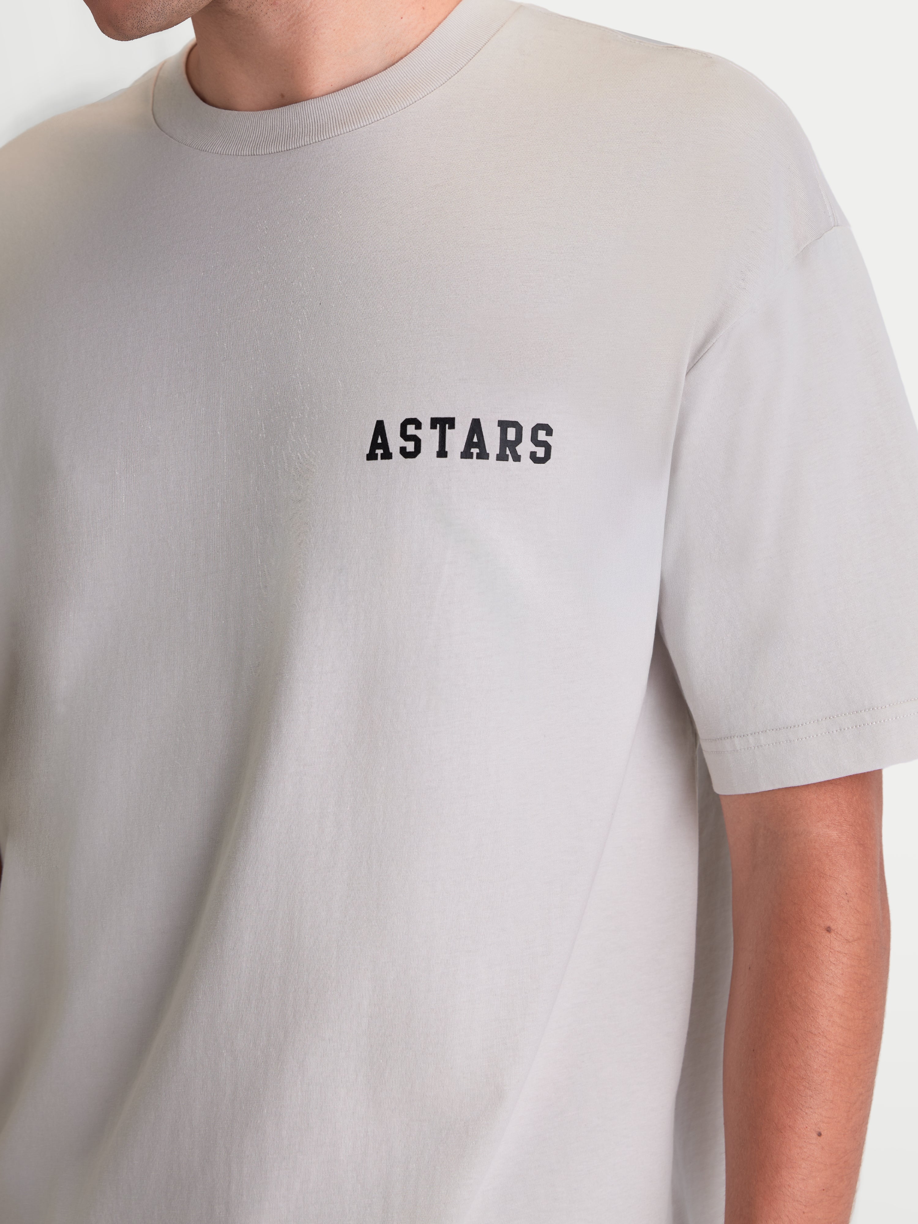 Alpinestars Latitude Oversized CSF T-shirt, kortærmet sportstøj, grå med sort ASTARS-ordmærke på brystet, afslappet oversized pasform, blød bomuldsblanding, set på model.