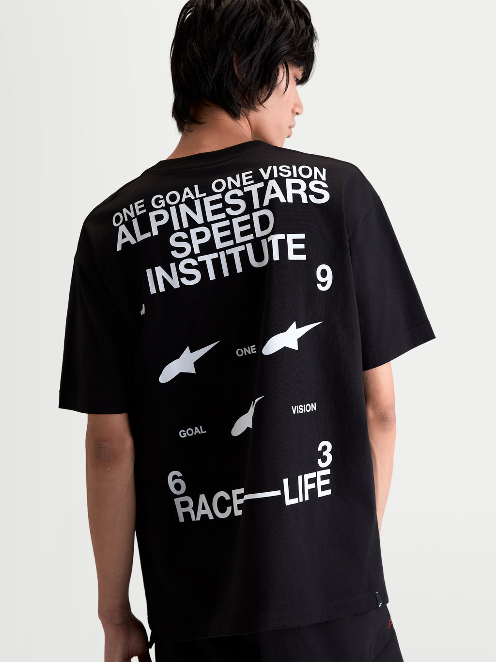 Alpinestars Institute Oversized CSF Tee, Black and White Sportswear T-Shirt, Rear View on Model showing 'Alpinestars Speed Institute' and 'Race-Life' back graphics, relaxed oversized fit, comfortable cotton-poly blend.