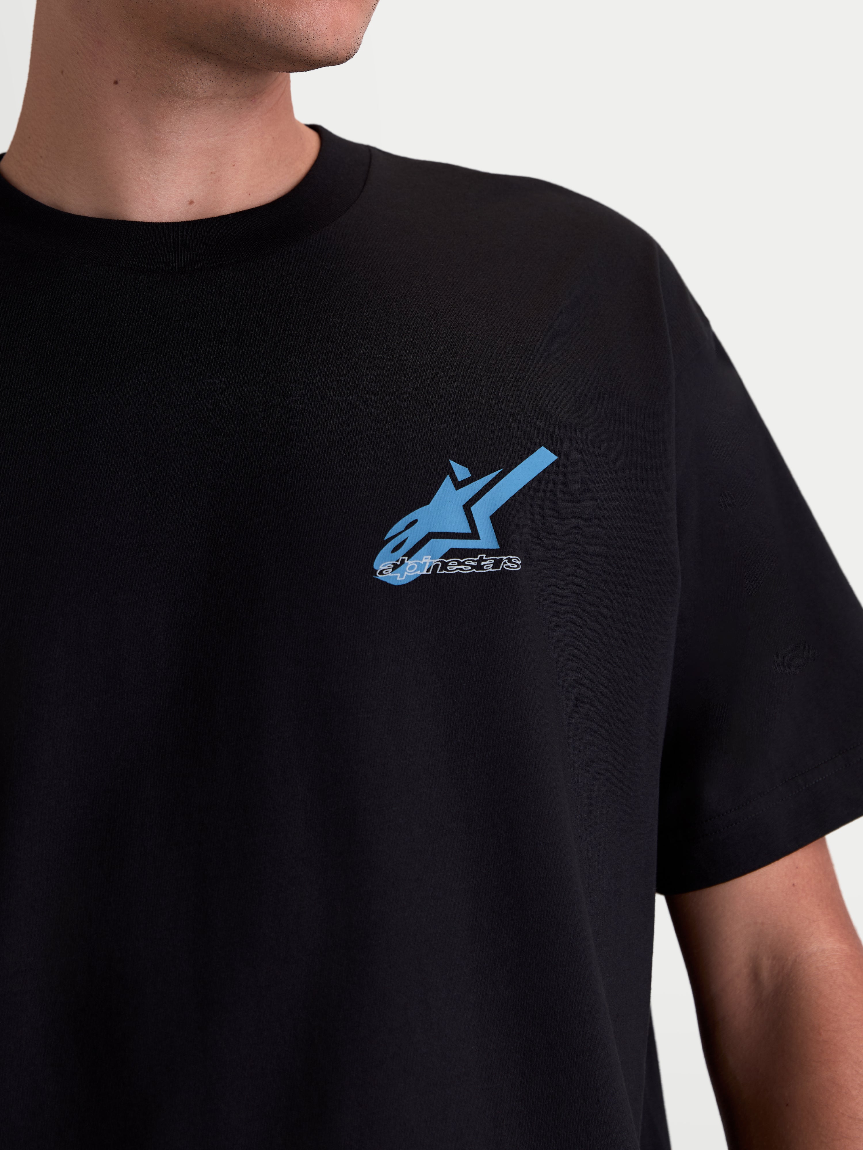 Alpinestars Ghost Oversized CSF Tee, Casual Sportswear Short Sleeve T-Shirt for Men and Women, Black with Blue and White Astars Logo Graphic on Chest, Premium Cotton-Poly Blend, Close-up View on Model
