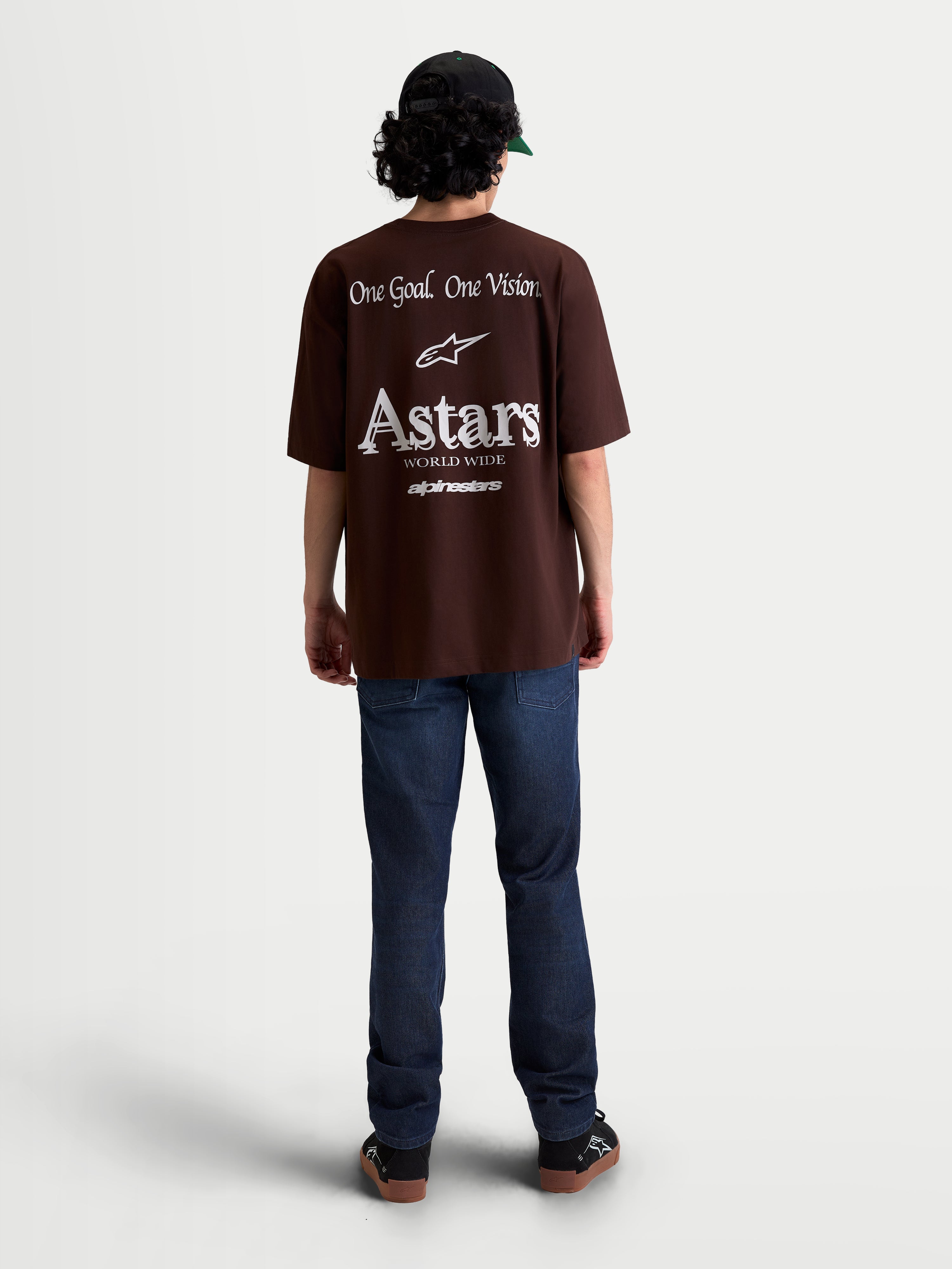 Alpinestars Post Oversized CSF T-shirt, brun kortærmet t-shirt i oversized fit, hvid grafik på ryggen med 'One Goal. One Vision.' og Astars World Wide branding, set bagfra på model, afslappet motorsport sportstøj og streetwear.
