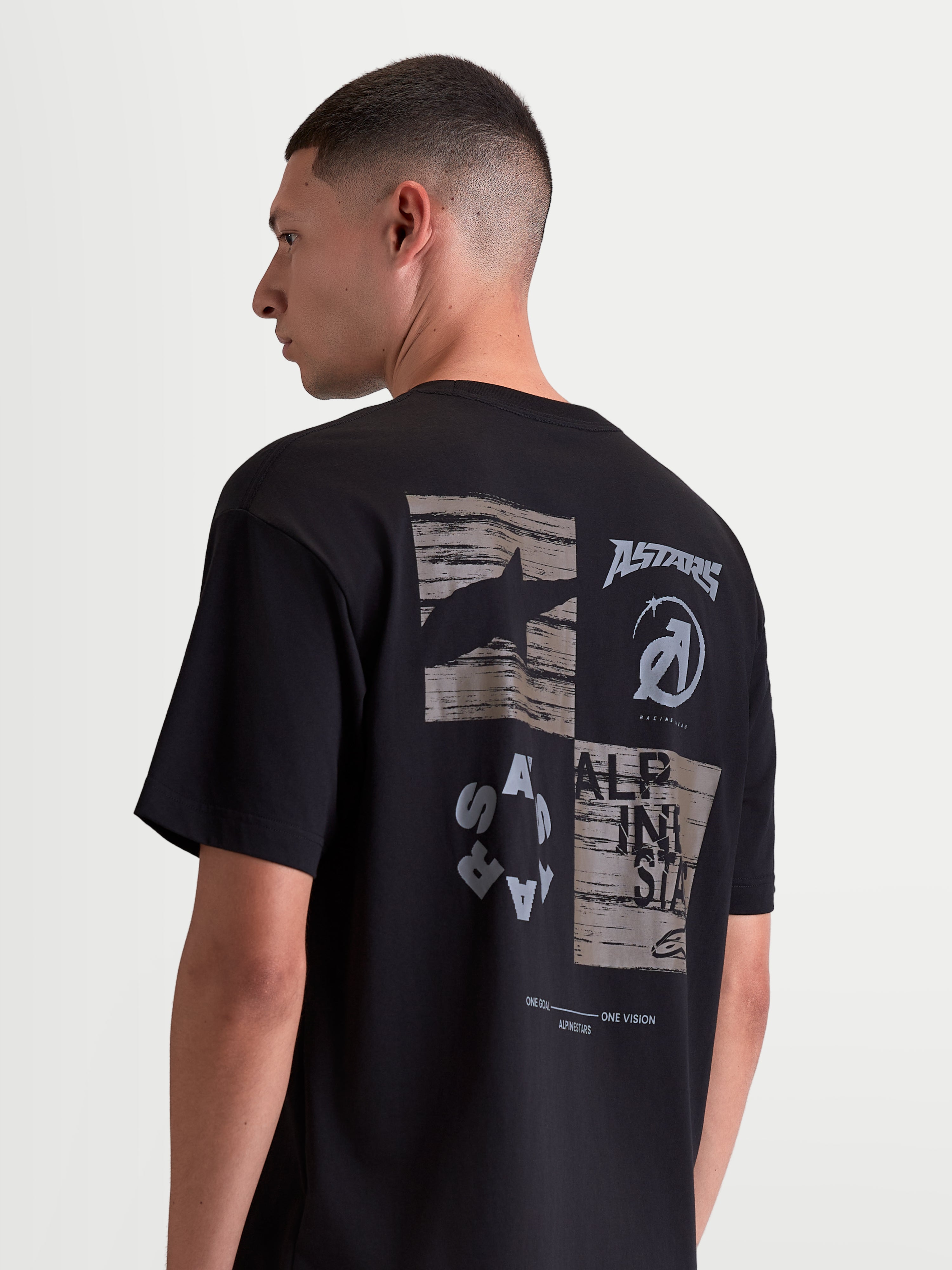 Alpinestars Checkback Oversized CSF T-shirt, sort og grå kortærmet sportswear T-shirt set bagfra på en model, markant motorsport-inspireret grafik på ryggen med Astars branding, afslappet oversized pasform.