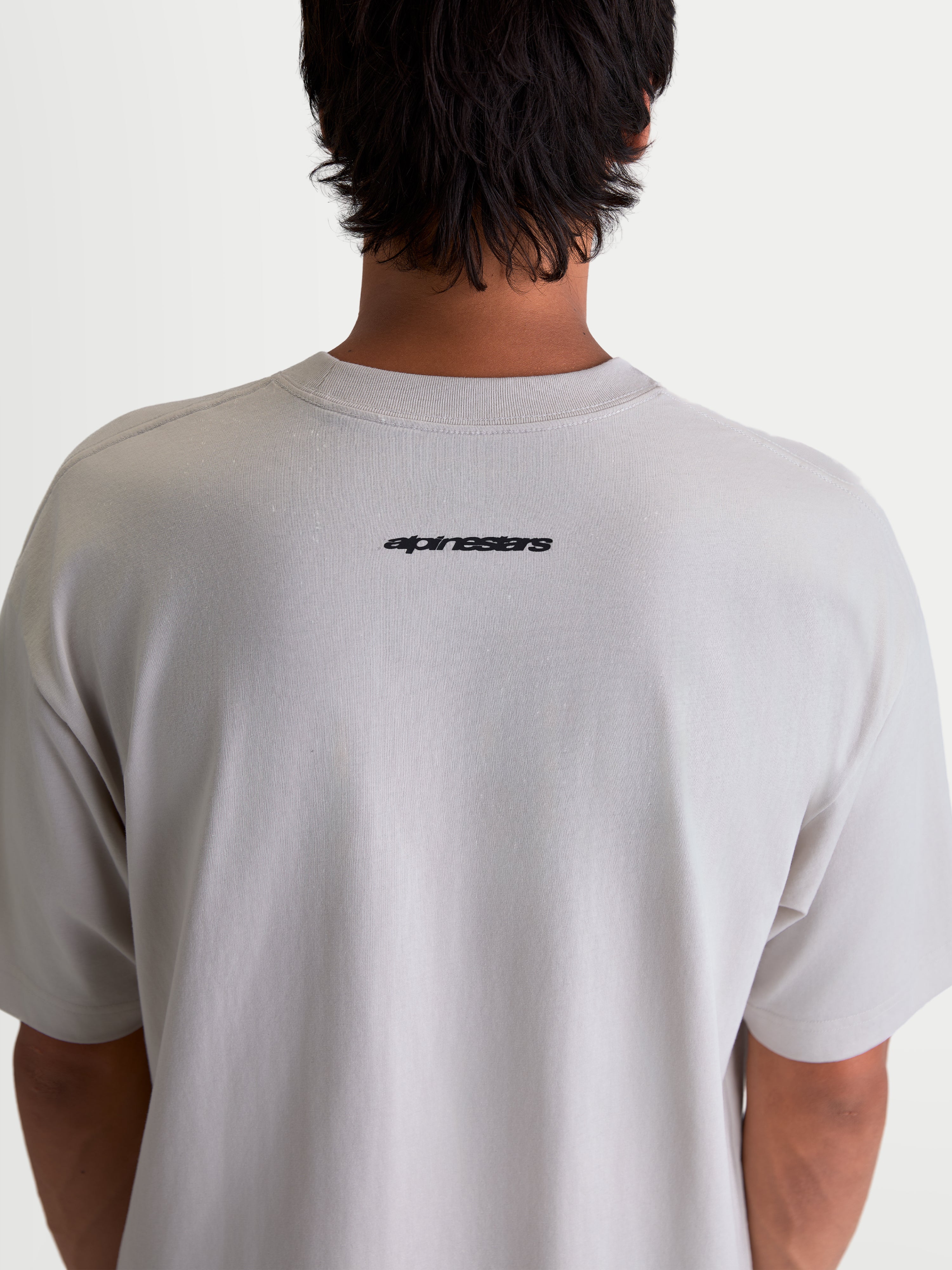 Alpinestars Mandate Oversized CSF T-Shirt, kortærmet T-shirt i grå, set bagfra på model med sort Alpinestars-logo på øvre ryg, oversized pasform, afslappet sportswear.