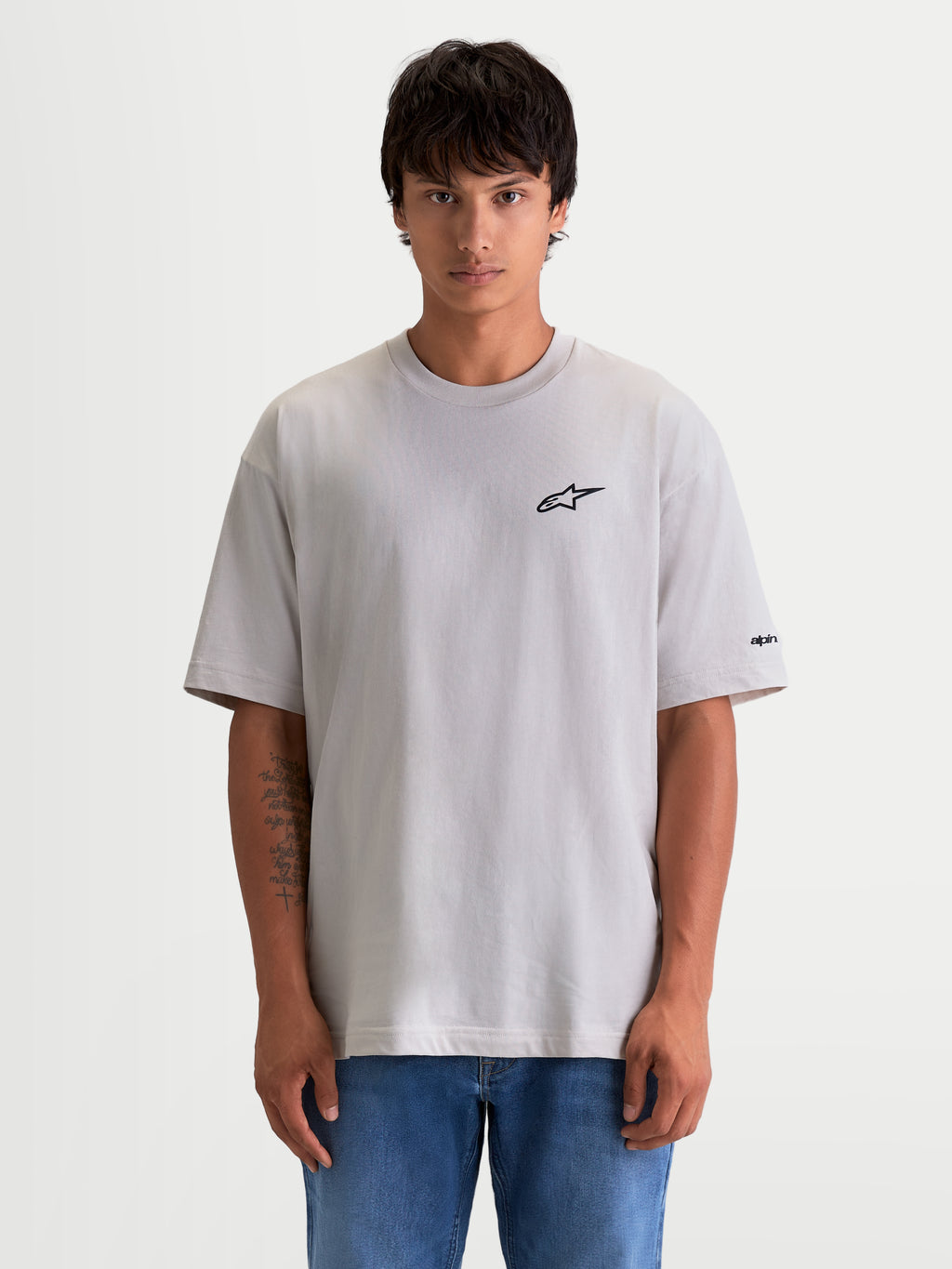 Alpinestars Mandate Oversized CSF t-shirt, kortærmet sportstøj til mænd og kvinder, cementgrå med sort puff-print Astars-logo, oversized afslappet pasform, bomuld-polyesterblanding, vist på model.