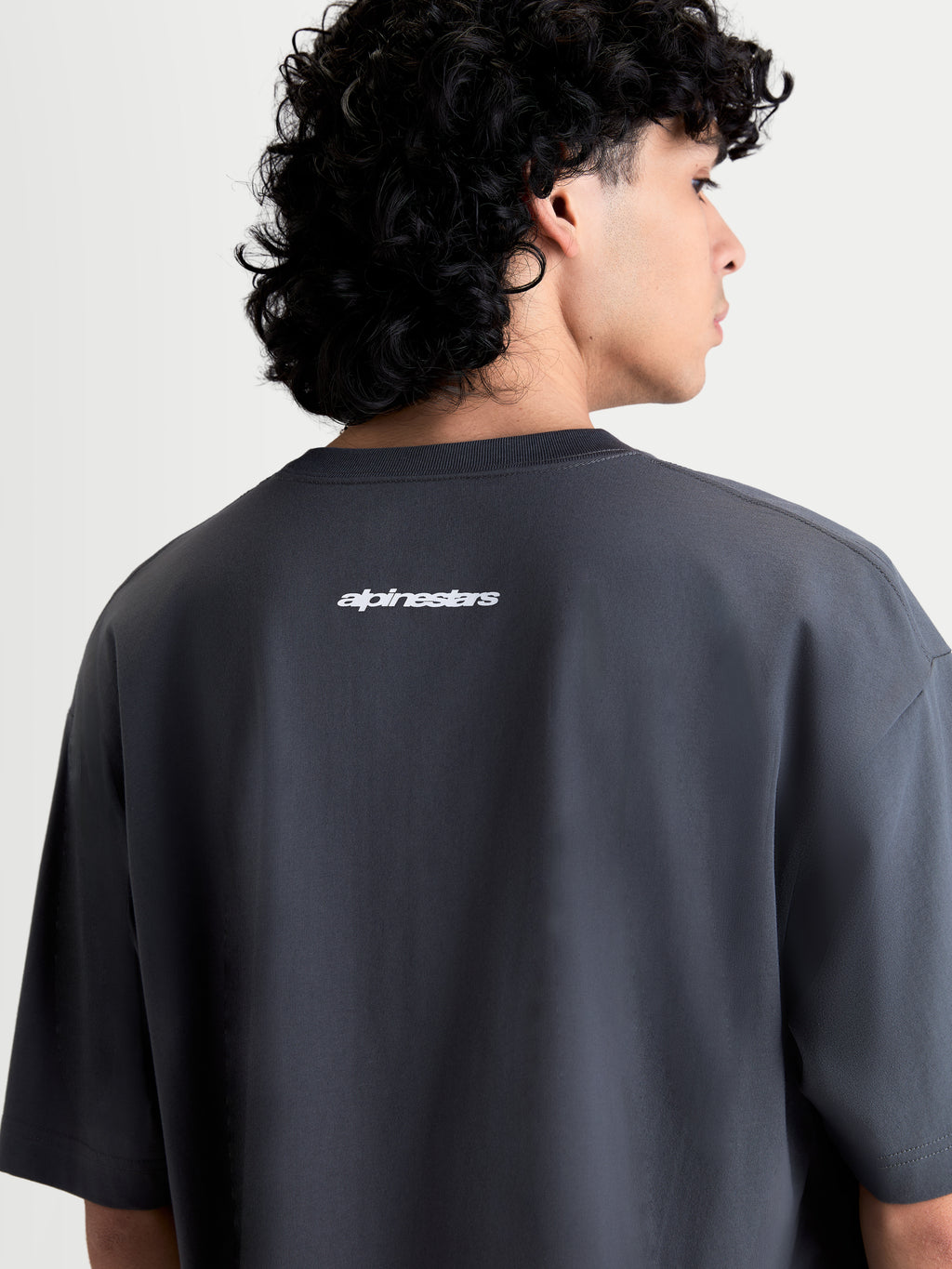 Alpinestars Mandate Oversized CSF T-shirt, grå kortærmet T-shirt til herrer og damer, set bagfra med hvidt puff-print Alpinestars ordmærke på ryggen, afslappet oversized pasform, blød bomulds-polyesterblanding, casual sportswear.