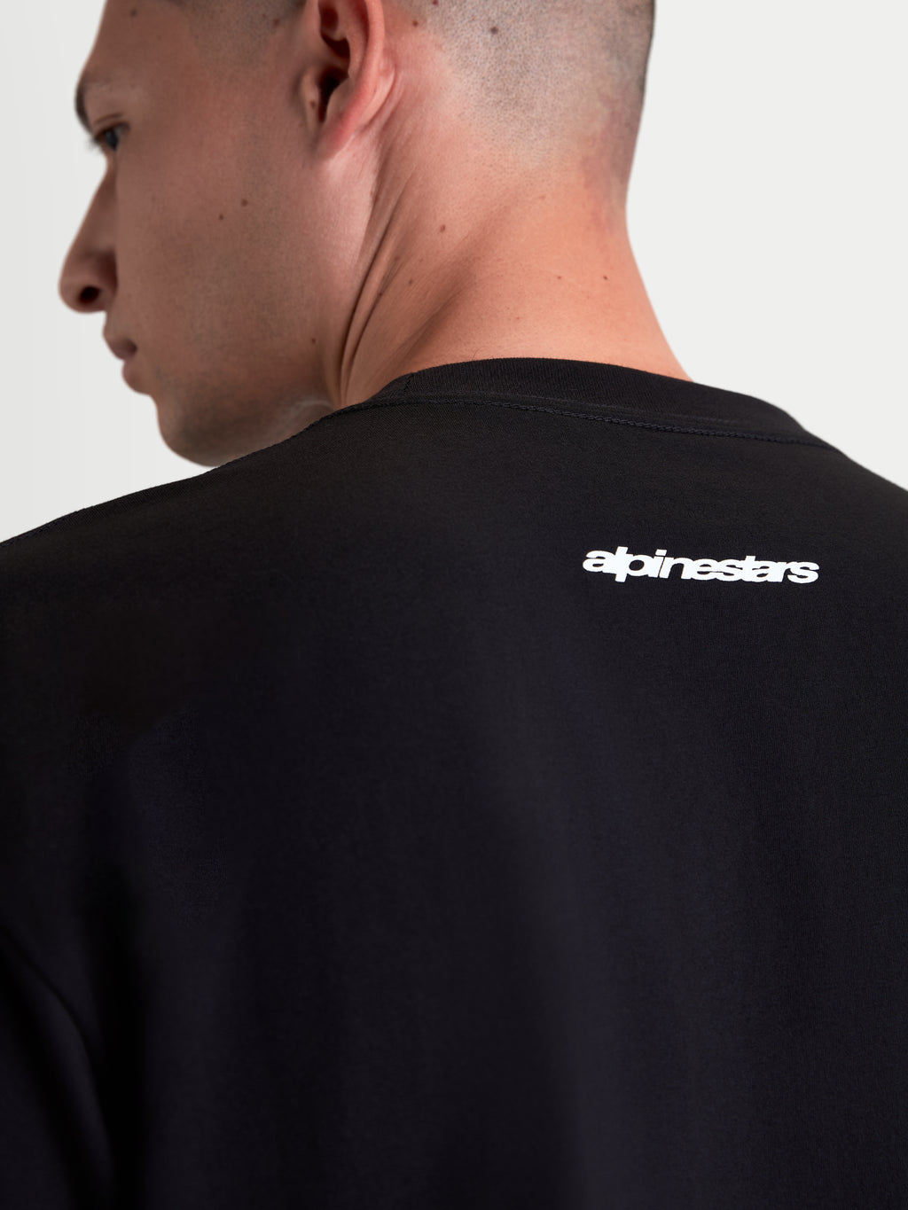 Alpinestars Prelude Oversized CSF T-shirt, sort kortærmet sportswear t-shirt til herrer og damer, nærbillede af hvidt Alpinestars-logografik på øvre ryg, oversized pasform, blød bomuldsblanding, afslappet motorsport-livsstil.