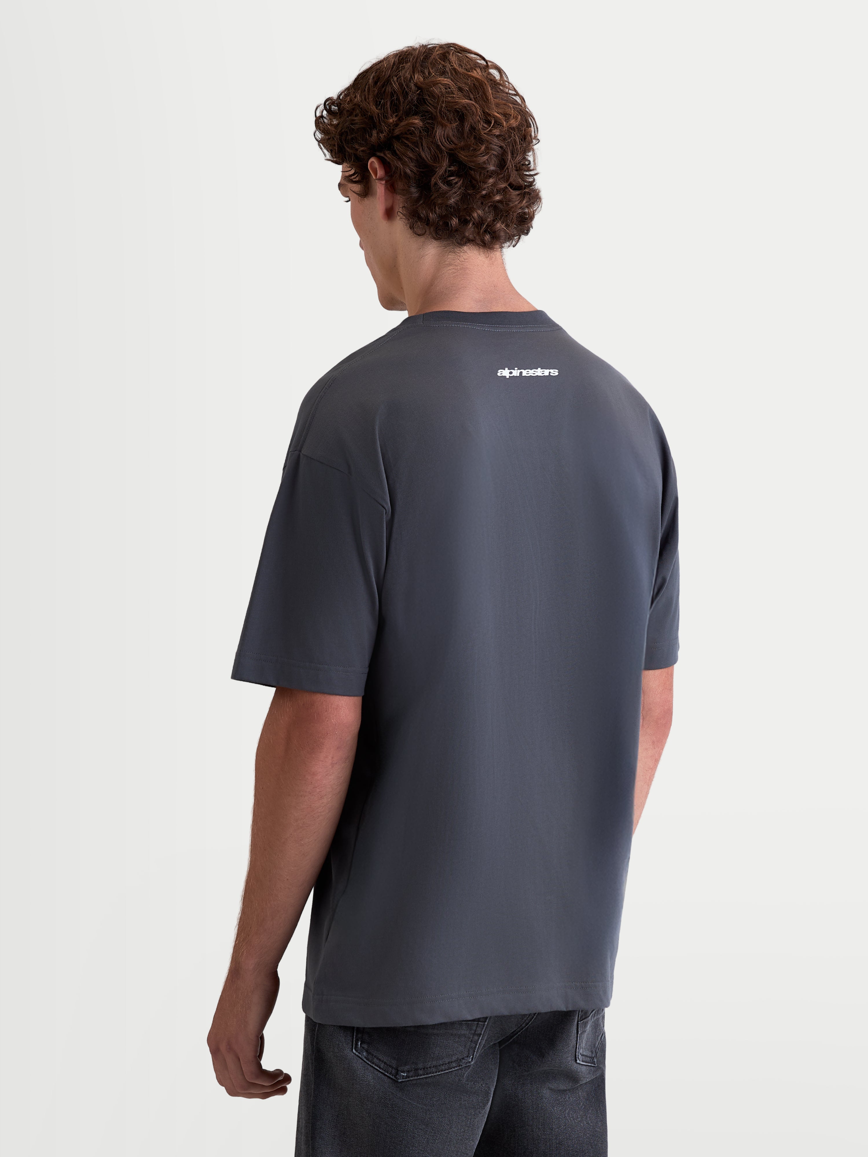 Alpinestars Prelude Oversized CSF Tee, Men's Sportswear Short Sleeve T-Shirt in Charcoal Gray, Rear View showing white Alpinestars logo graphic, relaxed oversized fit for casual wear.