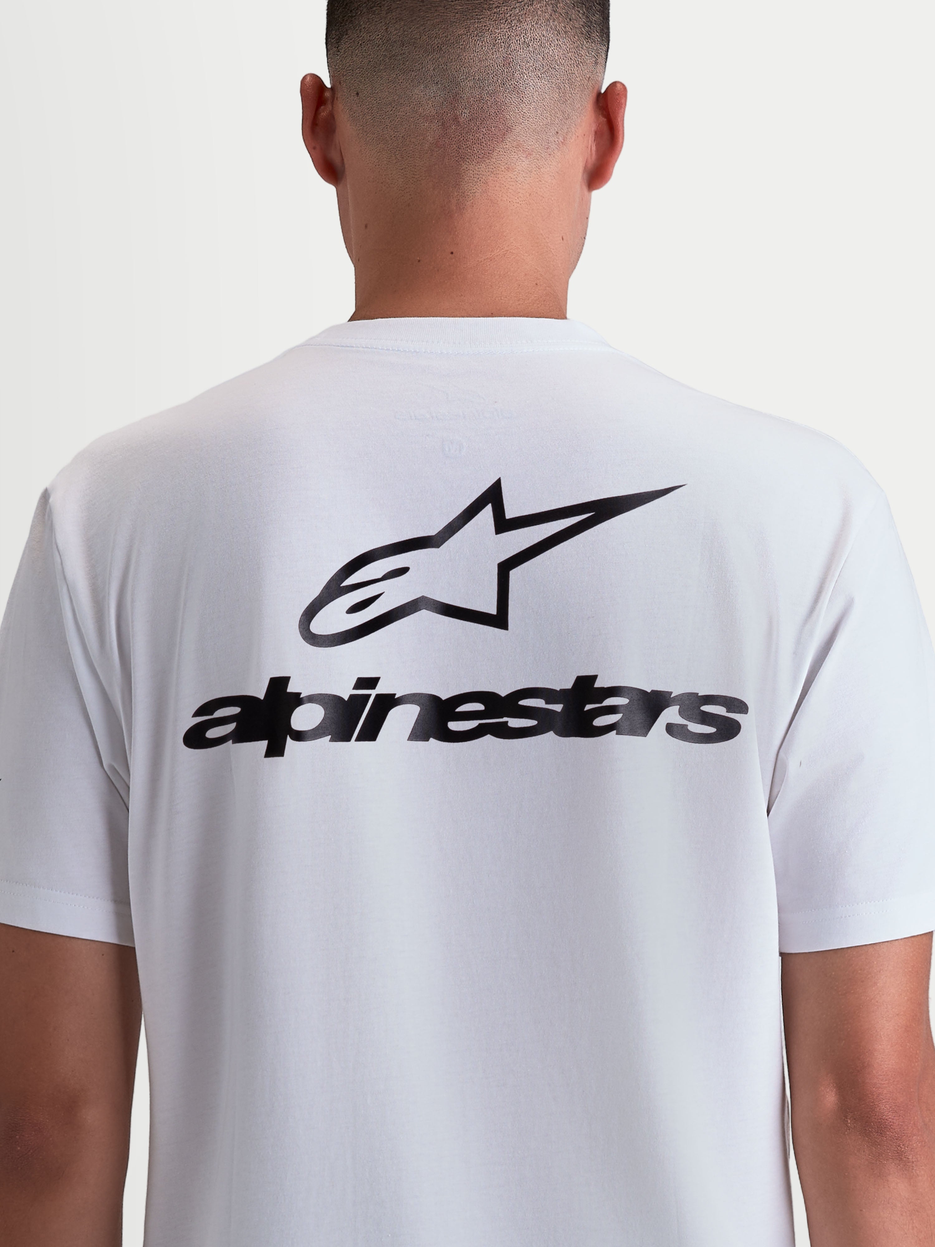 Alpinestars Combo Back CSF t-shirt, hvid kortærmet t-shirt set bagfra på model med stort sort Alpinestars logo og wordmark-grafik, premium bomulds-polyesterblanding, motorsport-inspireret sportstøj.