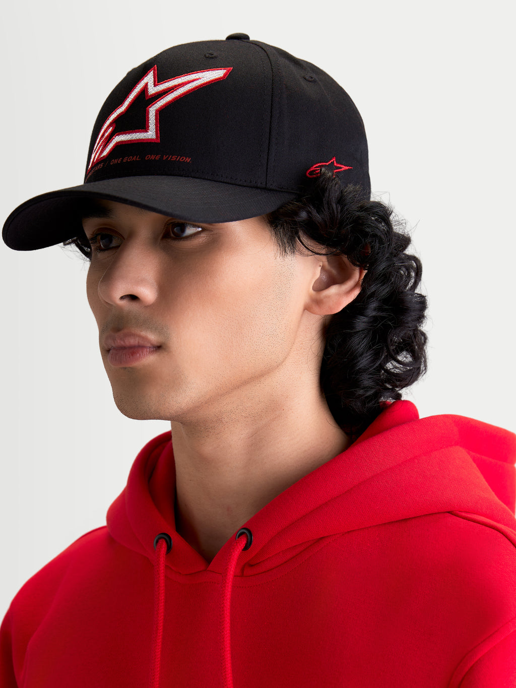 Alpinestars Lineout kasket, sort sportstøjskasket med buet skygge, struktureret krone med rød og hvidt broderet Astars-logo og sidebranding, vist på en model.