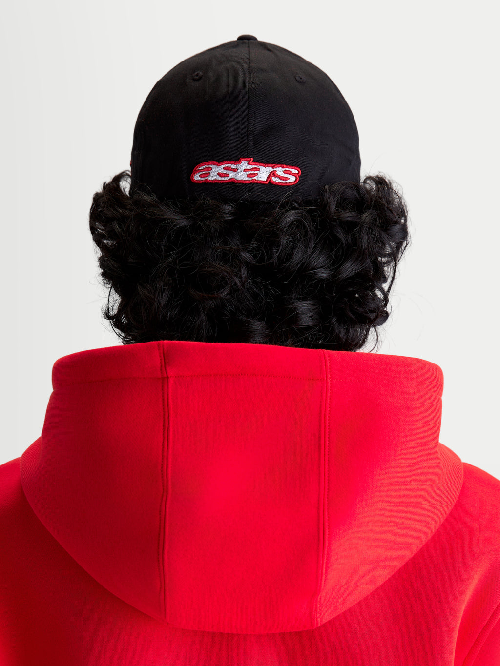Alpinestars Lineout kasket, sportswear baseballkasket, sort og rød, set bagfra på model med broderet Astars-logo, struktureret krone og twill-konstruktion.