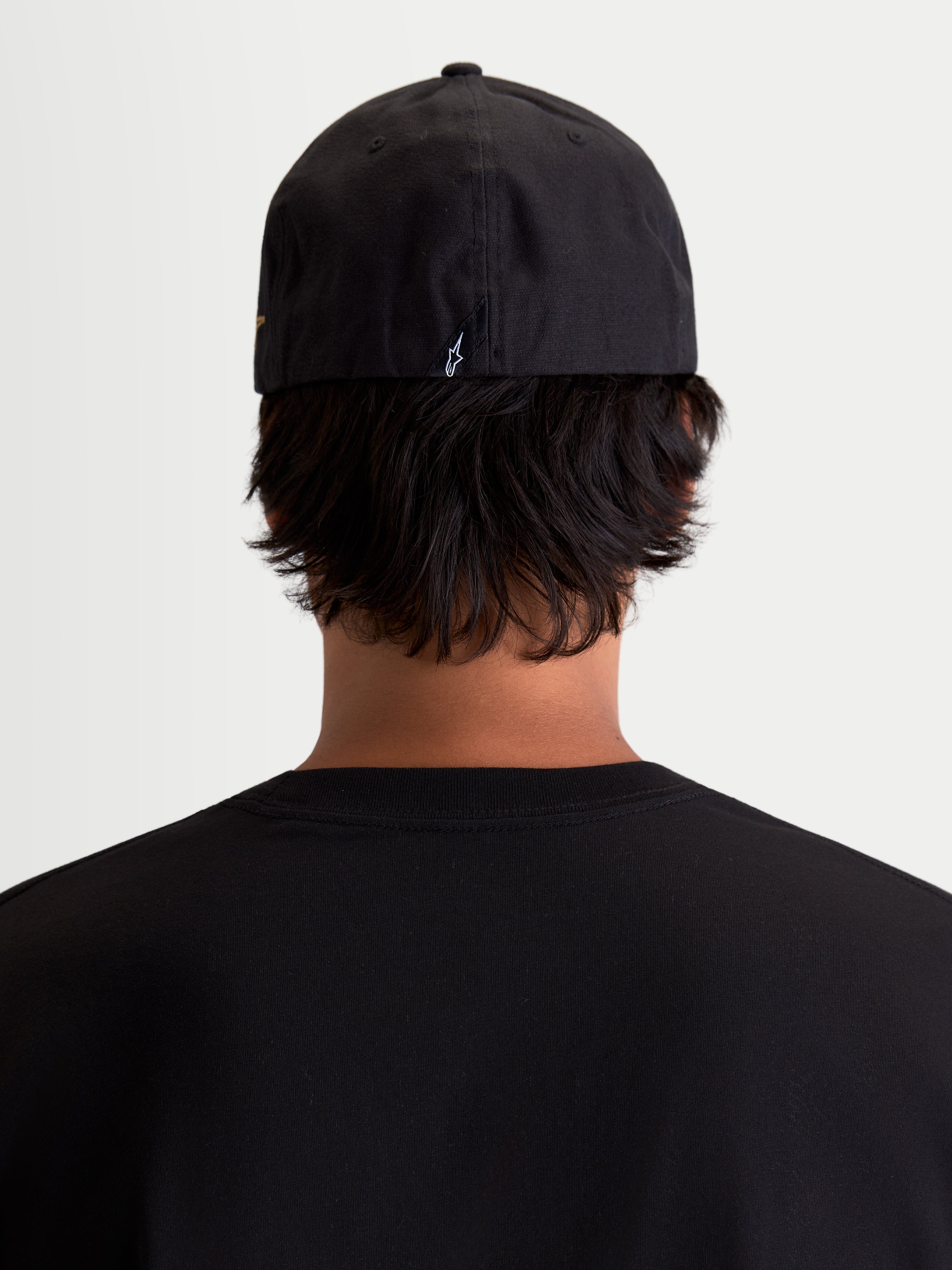 Alpinestars County Canvas kasket, sort sportswear-kasket set bagfra på model, med flex-back-pasform og lille broderet Astars-logo bagpå, peached oxford-stof.