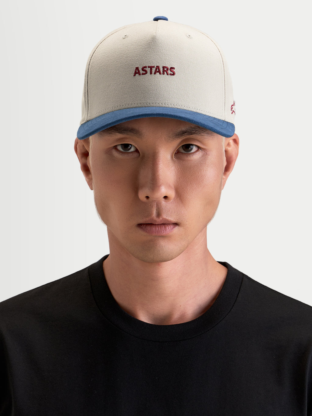Alpinestars County Canvas kasket, sandfarvet og blå sportswear-kasket med broderet Astars-logo foran, båret af mandlig model