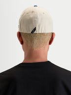Alpinestars County Canvas Kasket, sand og blå sportswear-kasket, bagfra båret af model med flex-back-pasform og diskret mærke med logo bagpå, peached oxford-bomuld