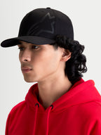 Alpinestars Maze kasket, sort motorsport-inspireret sportswear-kasket til herrer, med struktureret krone, buet skygge og tekstureret Astars Corp Shift-logo, set i profil på model.