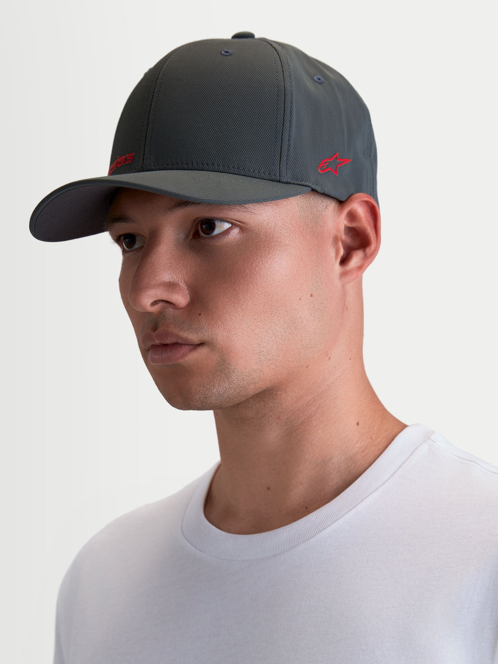 Alpinestars Points kasket på model, mørkegrå sportswear-kasket med bueformet skygge og rødt logo, let nylon tactel materiale, flex-back pasform til hverdagsbrug.