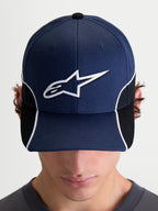 Alpinestars 500 Snapback Kasket, motorsport-inspireret sportswear-kasket, marineblå og sort, med buet skygge, 3D-broderet hvidt Astars-logo, hvid kontrastpiping og cut-and-sew-detaljer, set forfra på model.