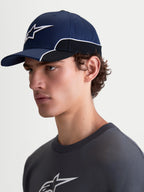 Alpinestars 500 Snapback kasket, sportswear baseball-kasket, unisex, marineblå og sort, slidstærk bomuldstwill, med buet skygge og 3D Astars-logo broderi med hvid kontrastpiping, set fra siden på en model.