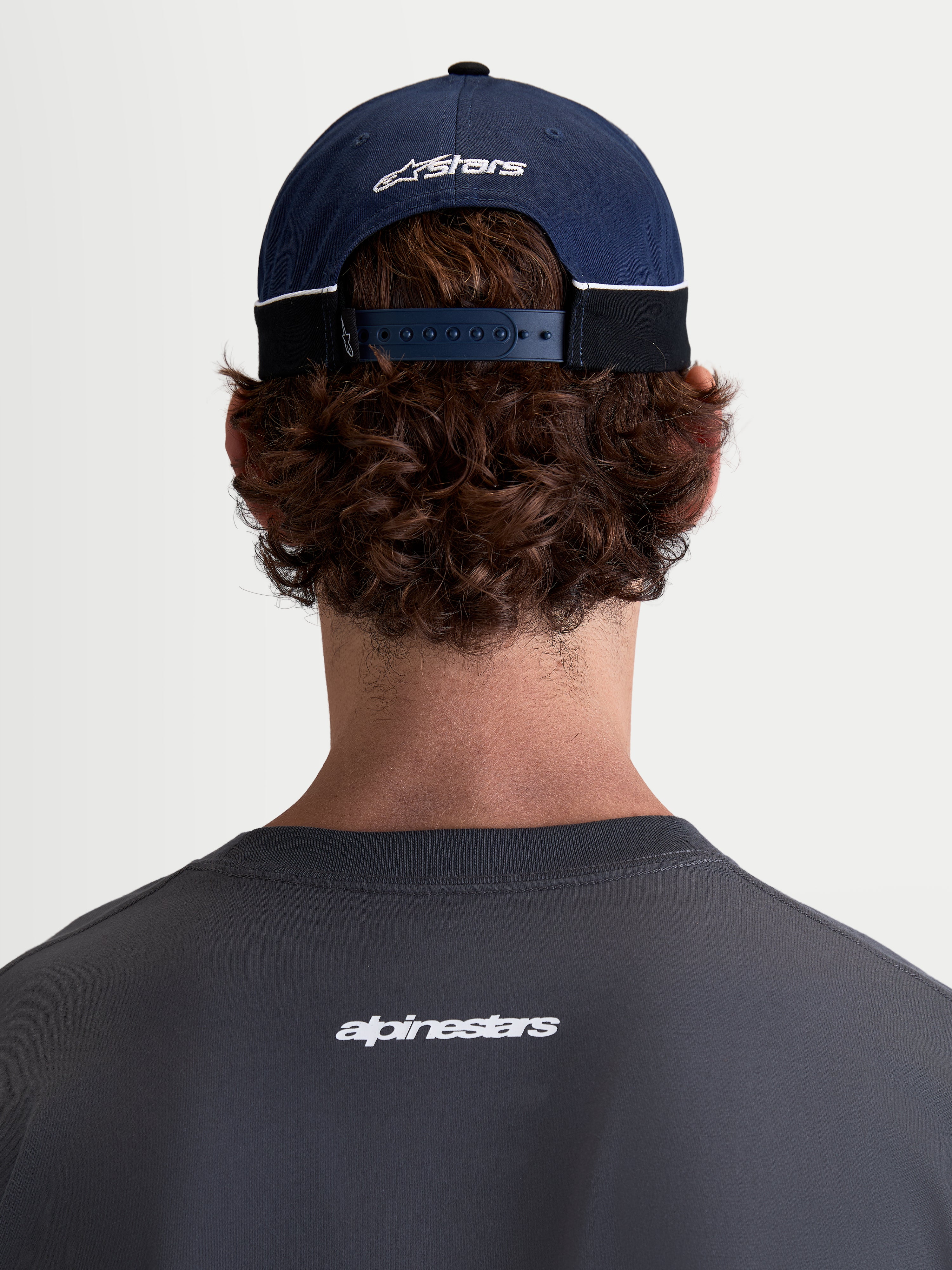Alpinestars 500 Snapback kasket, motorsport-inspireret sportswear baseballkasket i blå og sort, fremstillet i bomuldstwill med justerbar snapback-lukning og broderet Astars-logo bagpå, set bagfra på model.