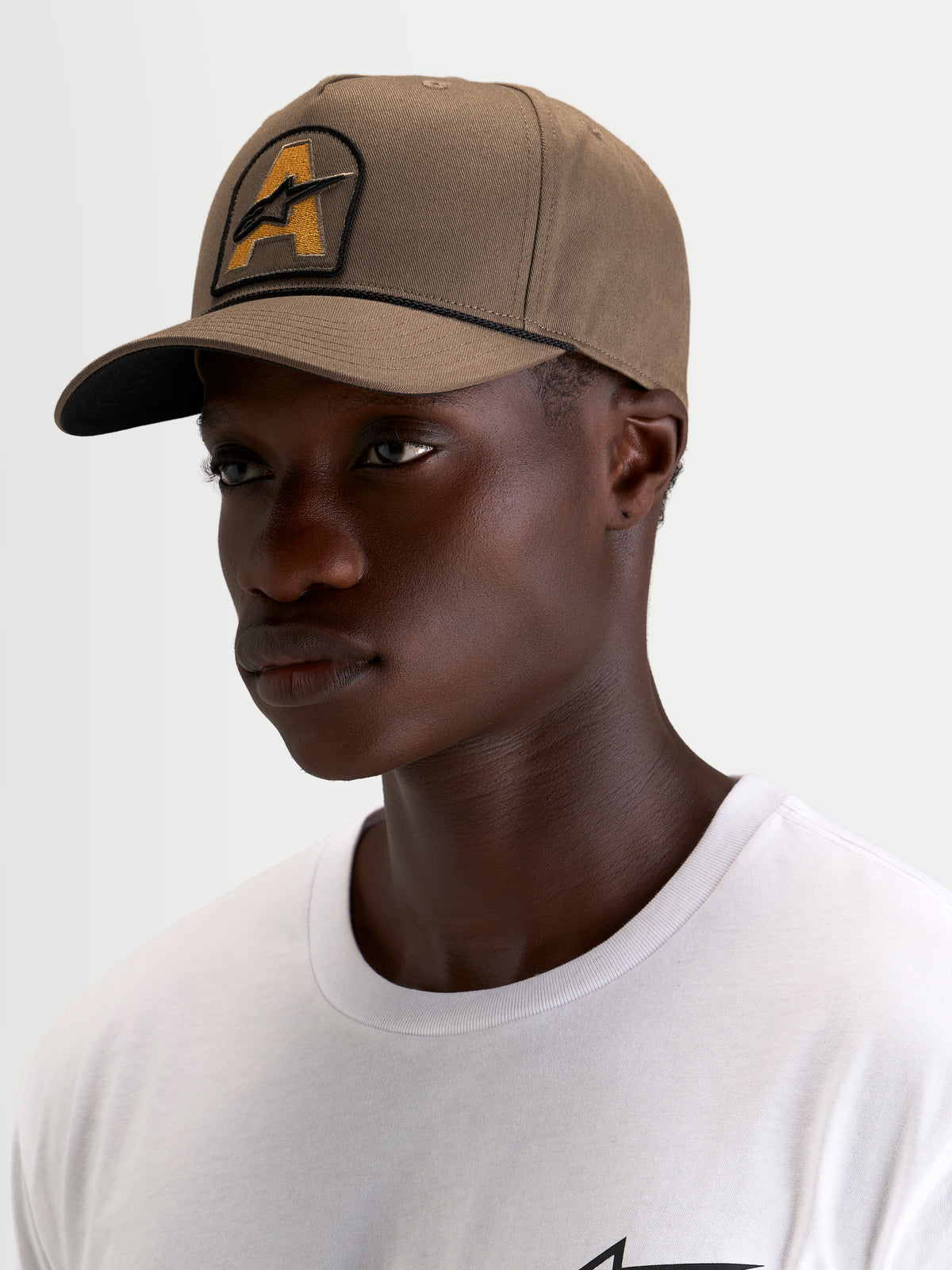 Alpinestars Acme Snapback Kasket, brun sportswear-kasket med buet skygge og broderet Astars-logopatch med rebkant, båret af model