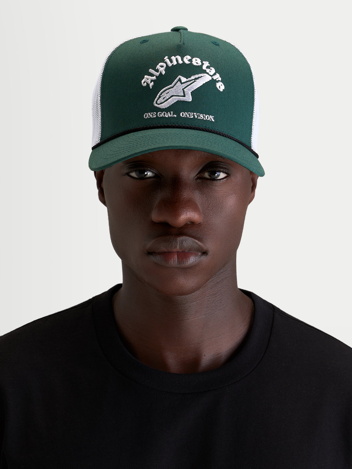 Alpinestars Baron Trucker Cap, grøn og hvid lifestyle kasket med buet skygge og mesh-bagside, båret af model