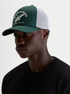 Alpinestars Baron Trucker Cap, grøn og hvid casual sportswear-kasket, båret af model med buet skygge, struktureret twill-krone og broderet logo foran
