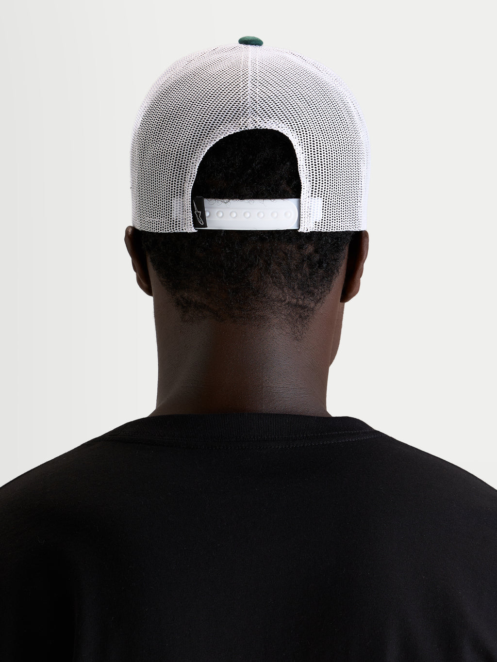 Alpinestars Baron Trucker Cap, hvid og grøn trucker cap, båret af model set bagfra med justerbar snapback-lukning og poly mesh-paneler