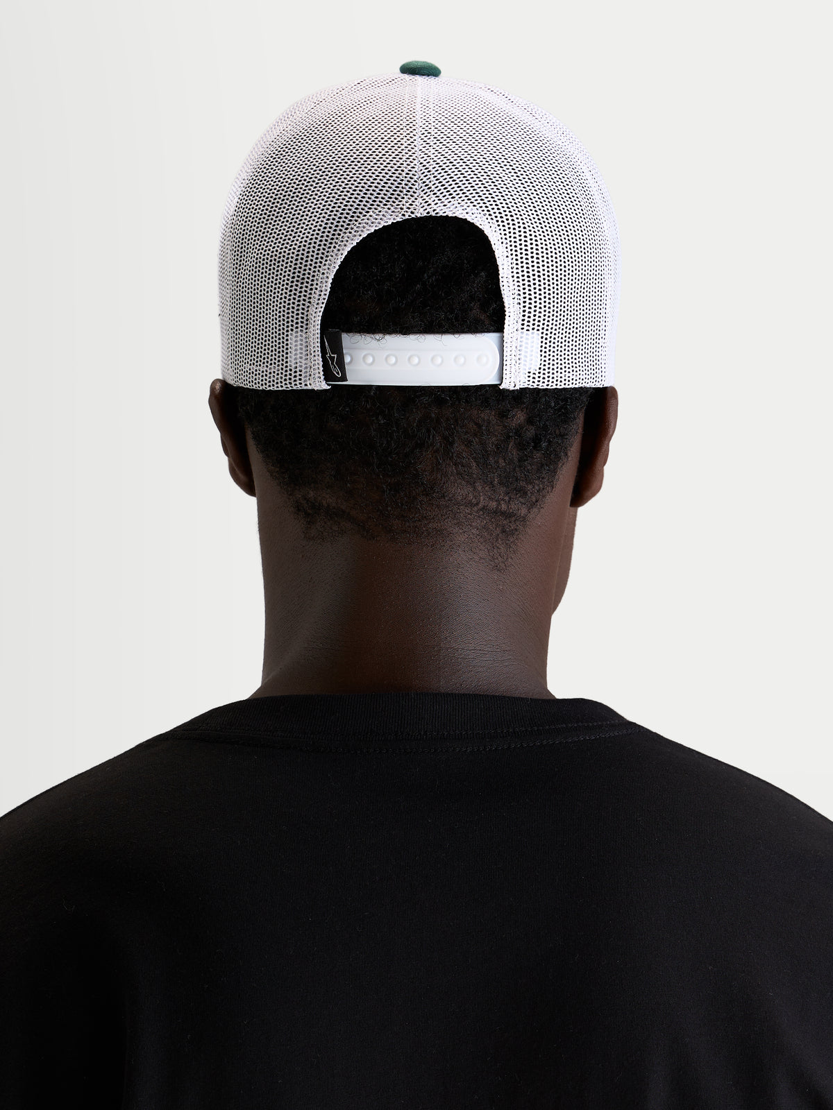 Alpinestars Baron Trucker Cap, hvid og grøn trucker cap, båret af model set bagfra med justerbar snapback-lukning og poly mesh-paneler