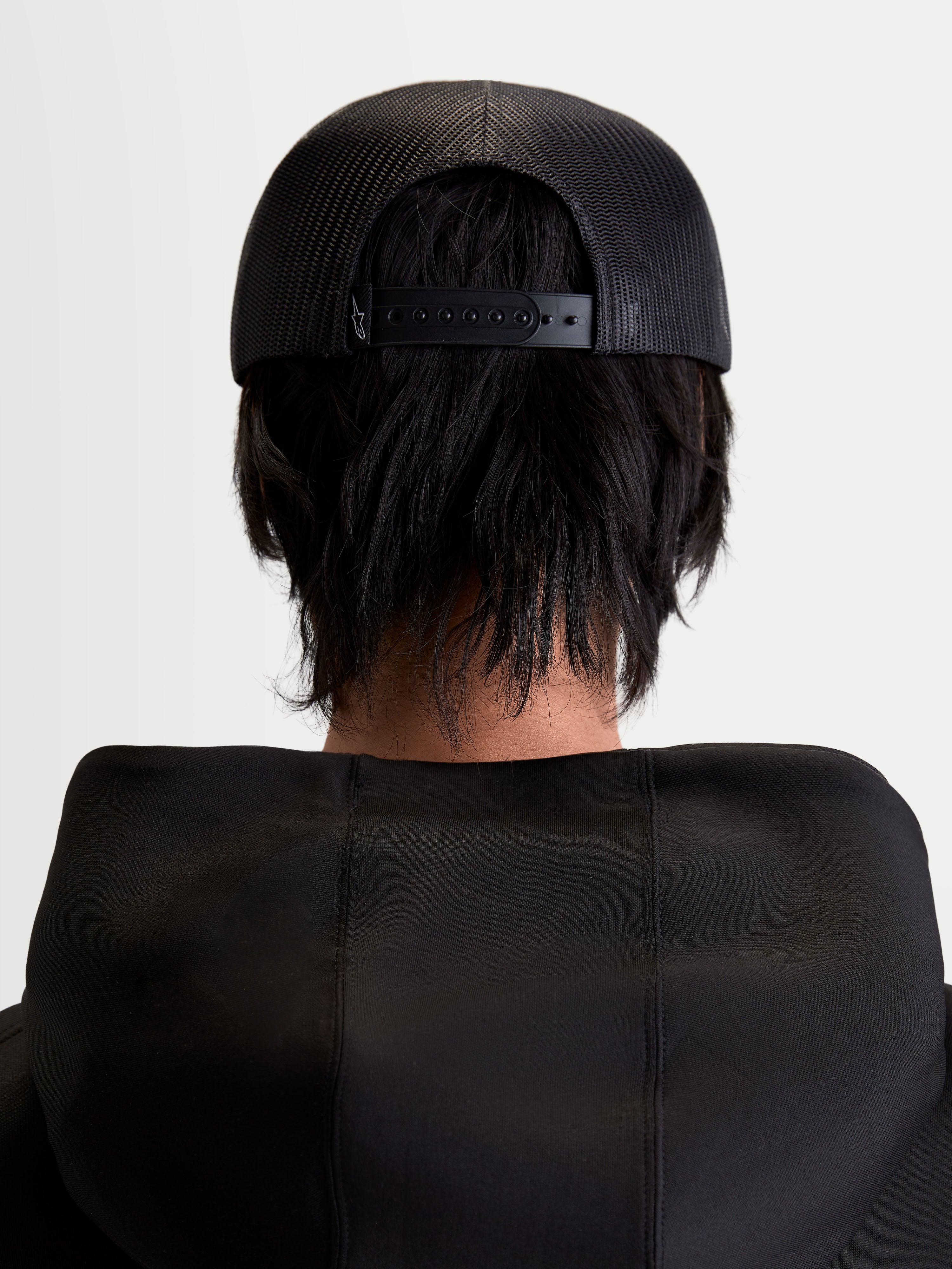 Alpinestars Gravel Trucker cap, sportswear snapback cap, sort, unisex, set bagfra på model med åndbar poly mesh-bagside og justerbar snapback-lukning.