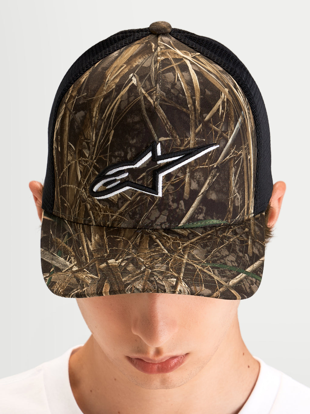 Alpinestars Thicket Realtree Trucker Hat, sportswear trucker cap worn by a model, Realtree camo and black, curved bill, structured crown, and white embroidered Astars logo on the front