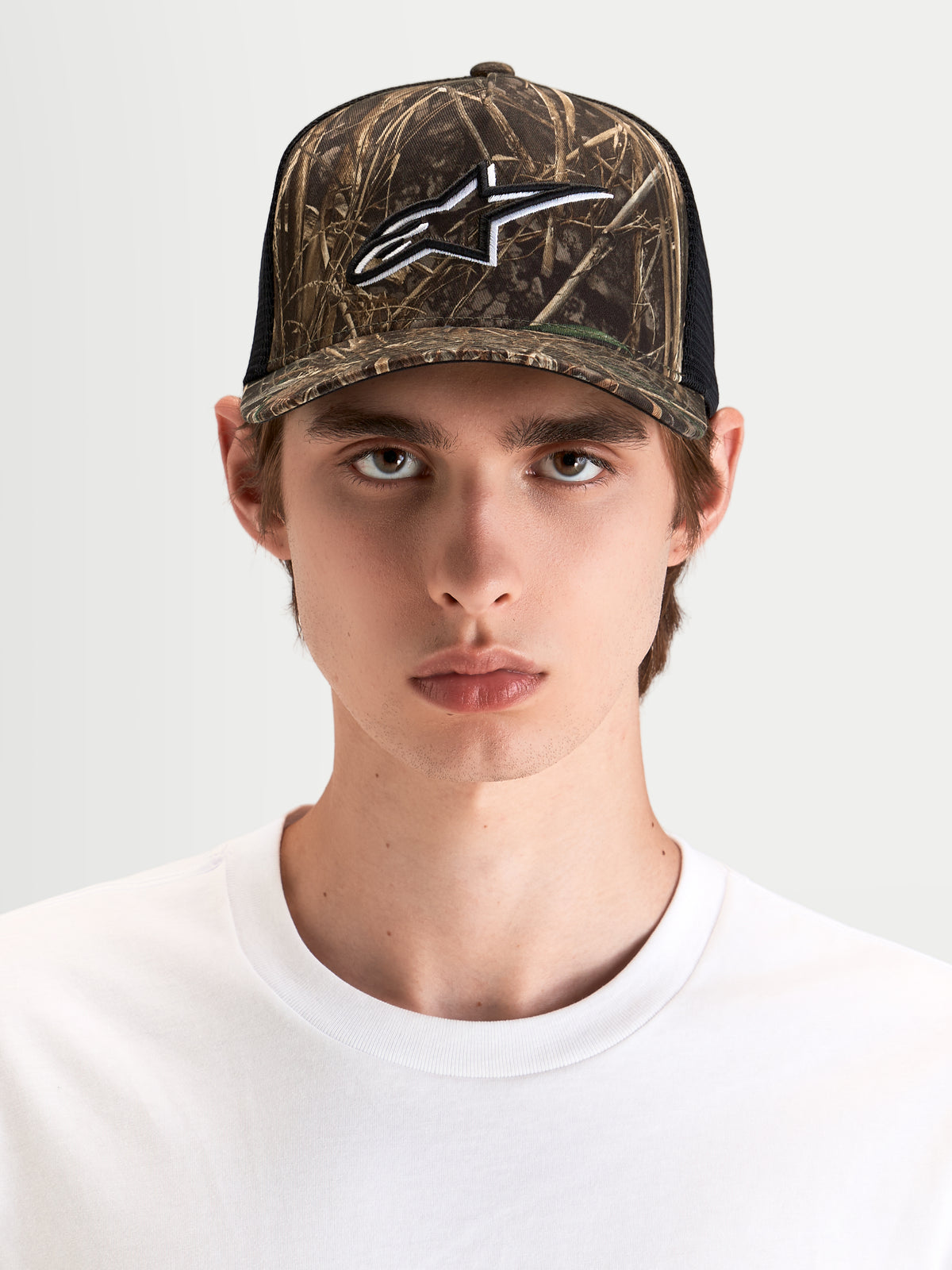 Alpinestars Thicket Realtree Trucker Cap, camouflage og sort trucker cap med struktureret krone og broderet Astars-logo på fronten, båret af mandlig model