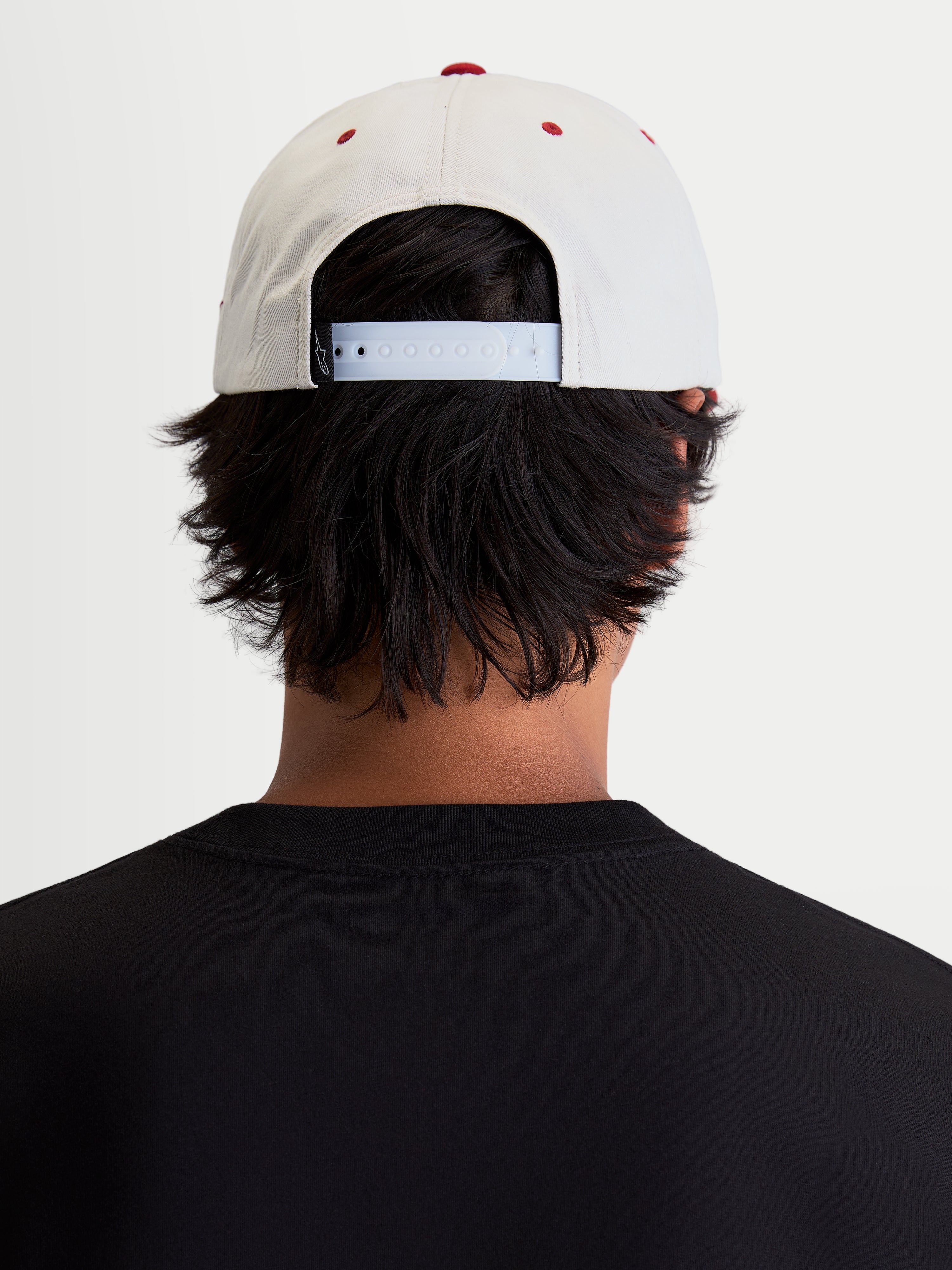 Alpinestars Stadium Snapback kasket, motorsport-inspireret sportstøj til hverdagsbrug, hvid og rød, justerbar snapback-lukning og struktureret krone, set bagfra på model.