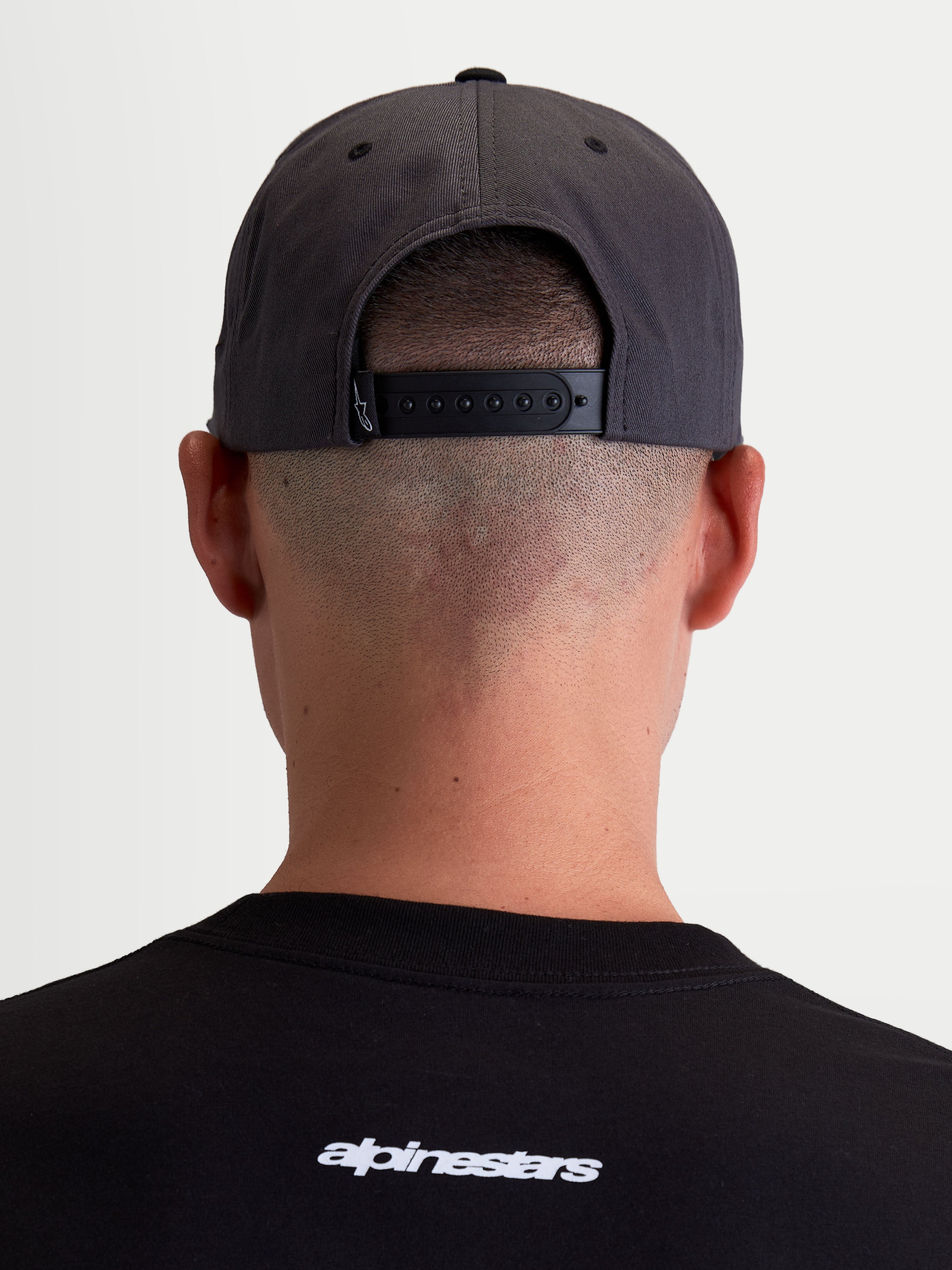 Alpinestars Stadium Snapback kasket, mørkegrå og sort sportswear-kasket, set bagfra på model der viser den justerbare snapback-lukning og strukturerede krone, slidstærk bomulds-twill.