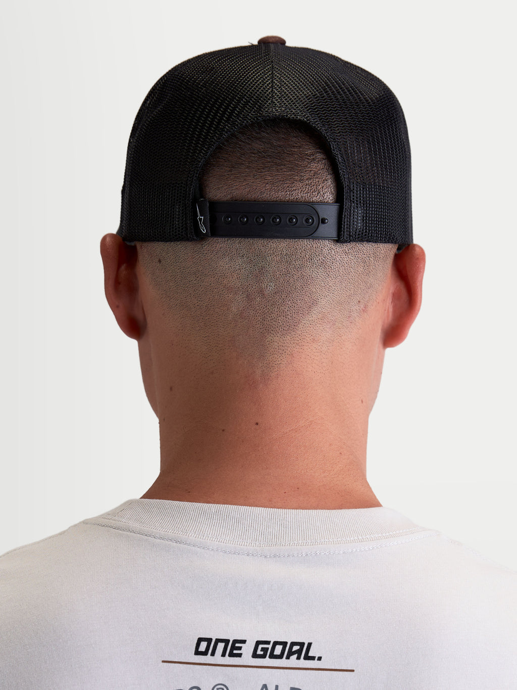 Alpinestars Hotlink Trucker Cap, motorsport-inspireret kasket, unisex, brun og sort, set bagfra på model med justerbar snapback-lukning, åndbare mesh-paneler og diskret branding.