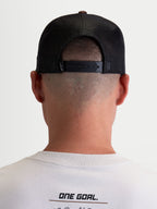 Alpinestars Hotlink Trucker Cap, motorsport-inspireret kasket, unisex, brun og sort, set bagfra på model med justerbar snapback-lukning, åndbare mesh-paneler og diskret branding.