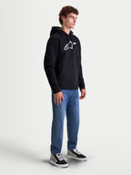 Alpinestars Ageless V3 hættetrøje, herrepullover til sportstøj, sort og hvid, med stort hvidt broderet logo på brystet, blød fleecekonstruktion, hætte med snoretræk og kængurulomme. Afslappet motorsportsinspireret hverdagstøj vist på model.