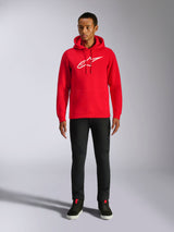 Alpinestars Ageless V3 hættetrøje, casual streetwear, rød med hvidt broderet Alpinestars-logo, båret af en mandlig model med sorte bukser, hætte med snoretræk, kængurulomme foran, moderne motorsport-inspireret design
