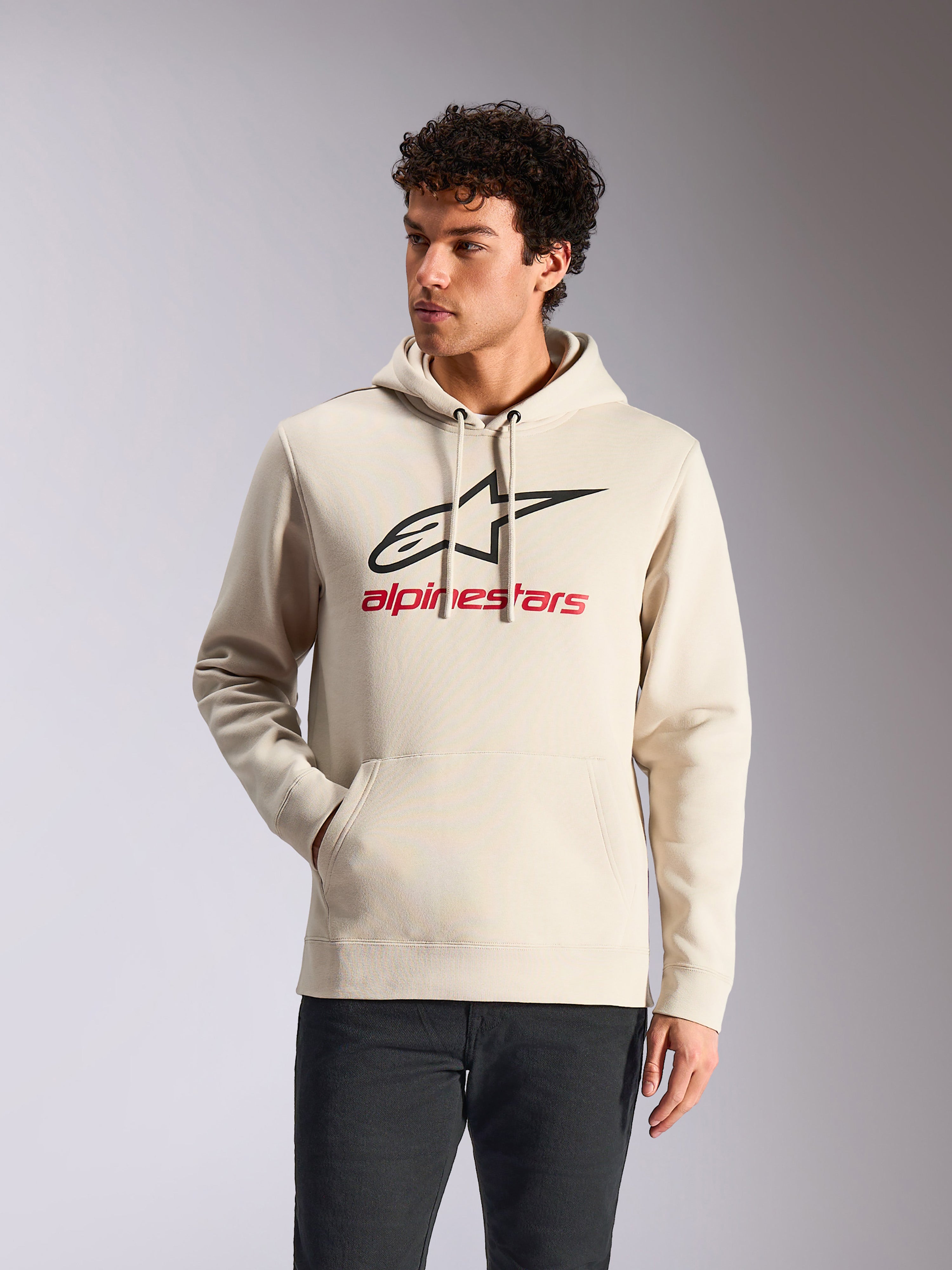 Alpinestars Always V3 hættetrøje, afslappet sportstøj, råhvid med sort stjernelogo og rød branding, hætte med snøre, kængurulomme foran, bæres af model med mørke bukser, moderne motorsport-inspireret design