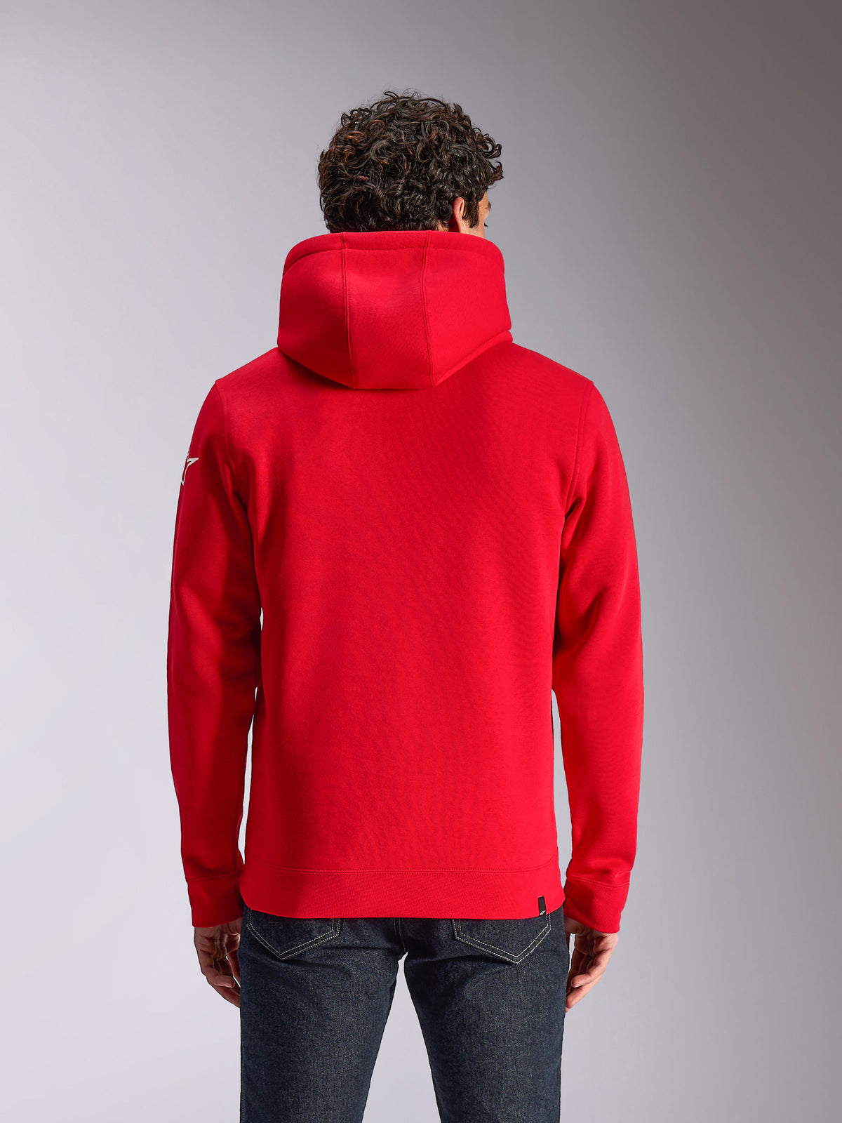 Alpinestars Linear Wordmark V3 hættetrøje, rød pullover-fleece set bagfra, hvidt Ageless-logo på ærmet, ribkanter og søm, afslappet motorsport-inspireret streetwear