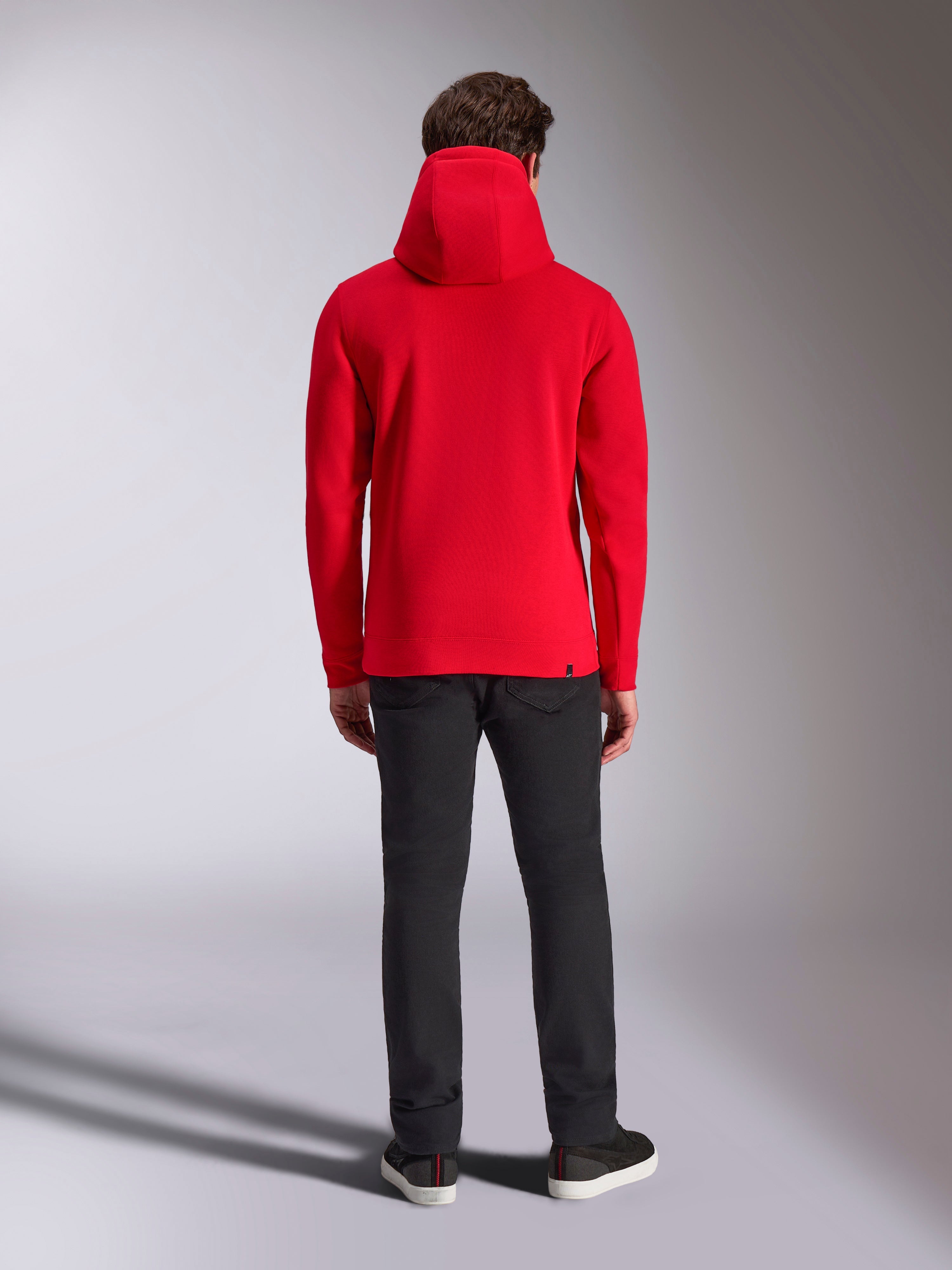 Alpinestars Ride V3 hættetrøje, set bagfra, ensfarvet rød, afslappet motorsport-inspireret fleece-hættetrøje, jersey-foret hætte, ribkanter ved manchetter og forneden, kombineret med sorte bukser og sneakers
