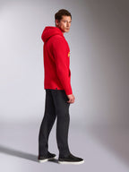 Alpinestars Ride V3 hættetrøje, afslappet sportstøj, rød med Hi-Vis gul branding, mandlig model iført rød hættetrøje med sorte bukser og sneakers, profilvisning fra siden, pullover fleece-design med ribkanter ved håndled og forneden.