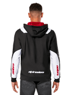 Alpinestars Sessions V3 Hoodie, back view, black with white sleeve panels and red hood lining, featuring white back wordmark and red sleeve branding, casual motorsport-inspired streetwear