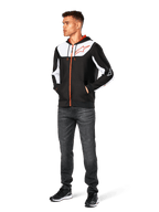 Alpinestars Sessions V3 Hoodie, casual zip-front hoodie, Black White and Red, worn by model with dark jeans and black sneakers, featuring white color-block panels on the chest and sleeves, red zipper and drawcord details, large chest logo, poly fleece motorsport-inspired streetwear