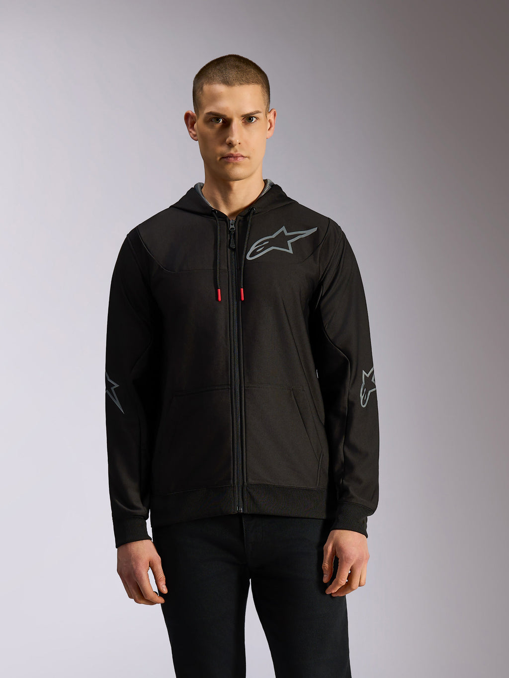 Alpinestars Sessions V3 Hoodie, hættetrøje med lynlås foran i polyester-fleece, sort og grå, grå stjernelogoer på brystet og albuerne, tekniske snøretræk med røde spidser, afslappet motorsport streetwear-stil.