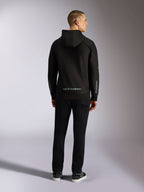 Alpinestars Sessions V3 hættetrøje, afslappet streetwear, sort med gråt Alpinestars-navnetræk på den nederste del af ryggen og 'astars'-branding på ærmerne, mandlig model set bagfra iført hættetrøje og sorte bukser, moderne motorsport-inspireret design